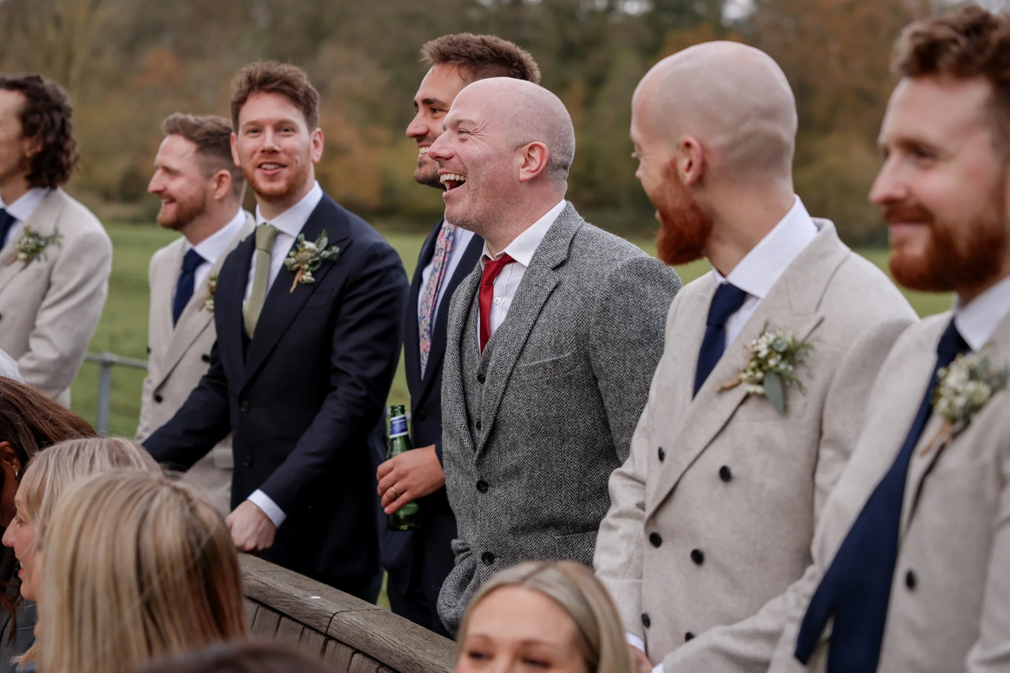 A group of men dressed in wedding attire, standing outdoors and smiling during a wedding celebration.