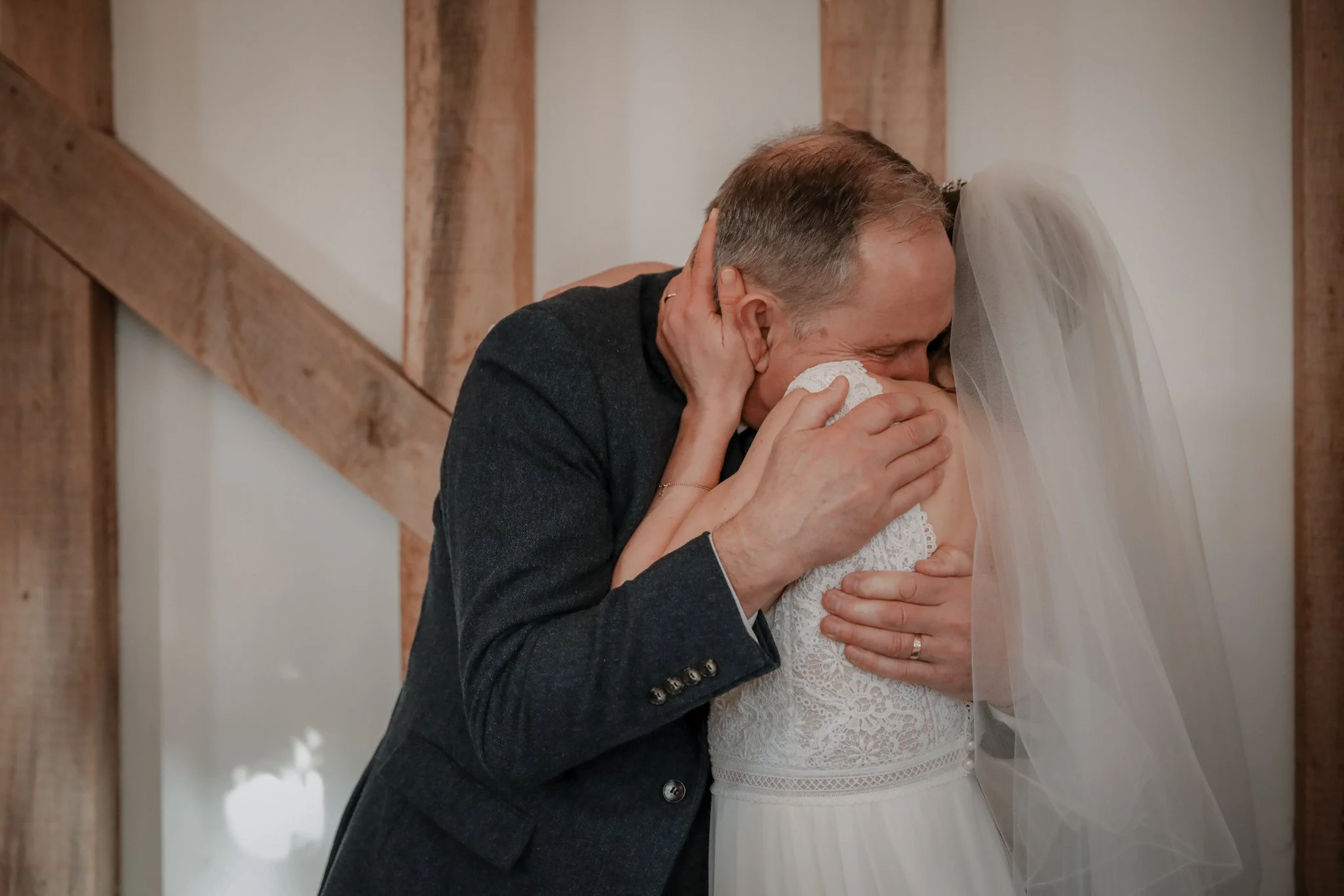 A man kissing a woman, dressed in a wedding gown, during a wedding ceremony indoors.