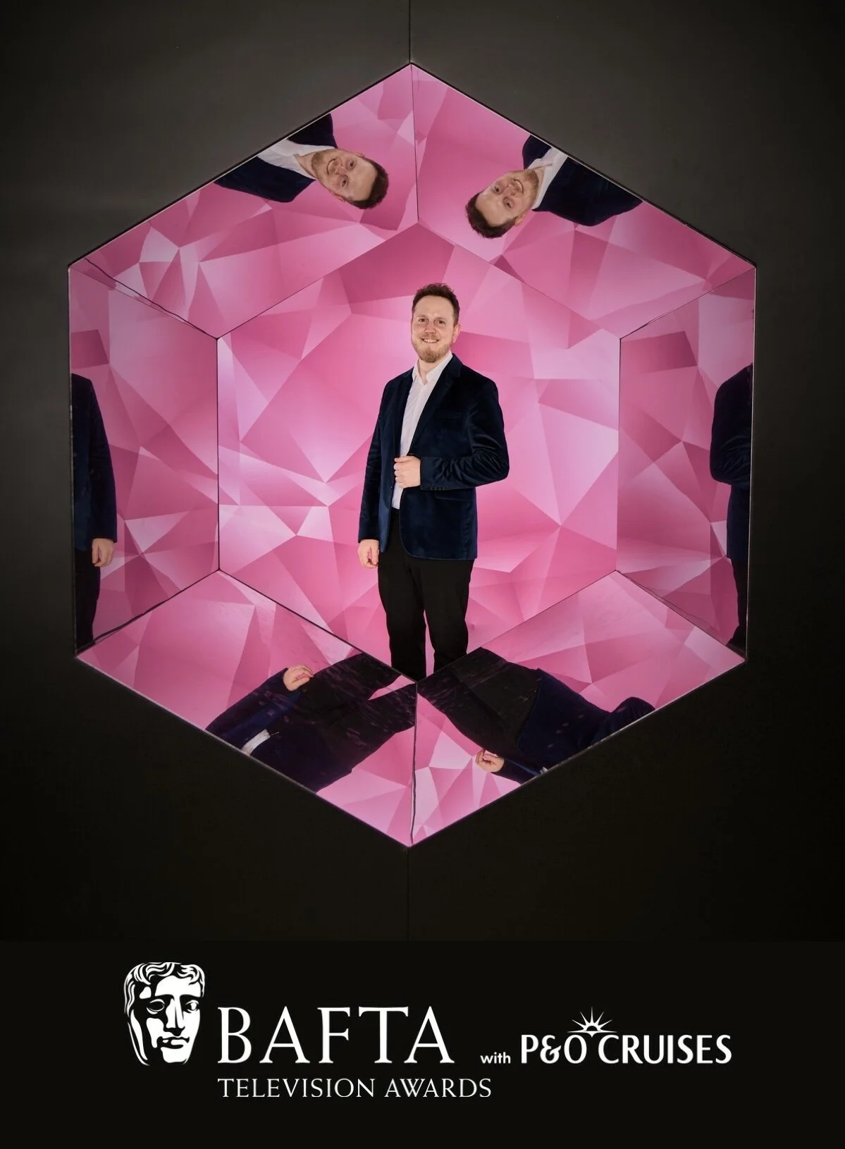 Moritz Valero in a suit standing inside a mirrored, geometric-shaped installation with pink patterned panels reflecting his image multiple times. The bottom of the image features the logos for BAFTA TV Awards.