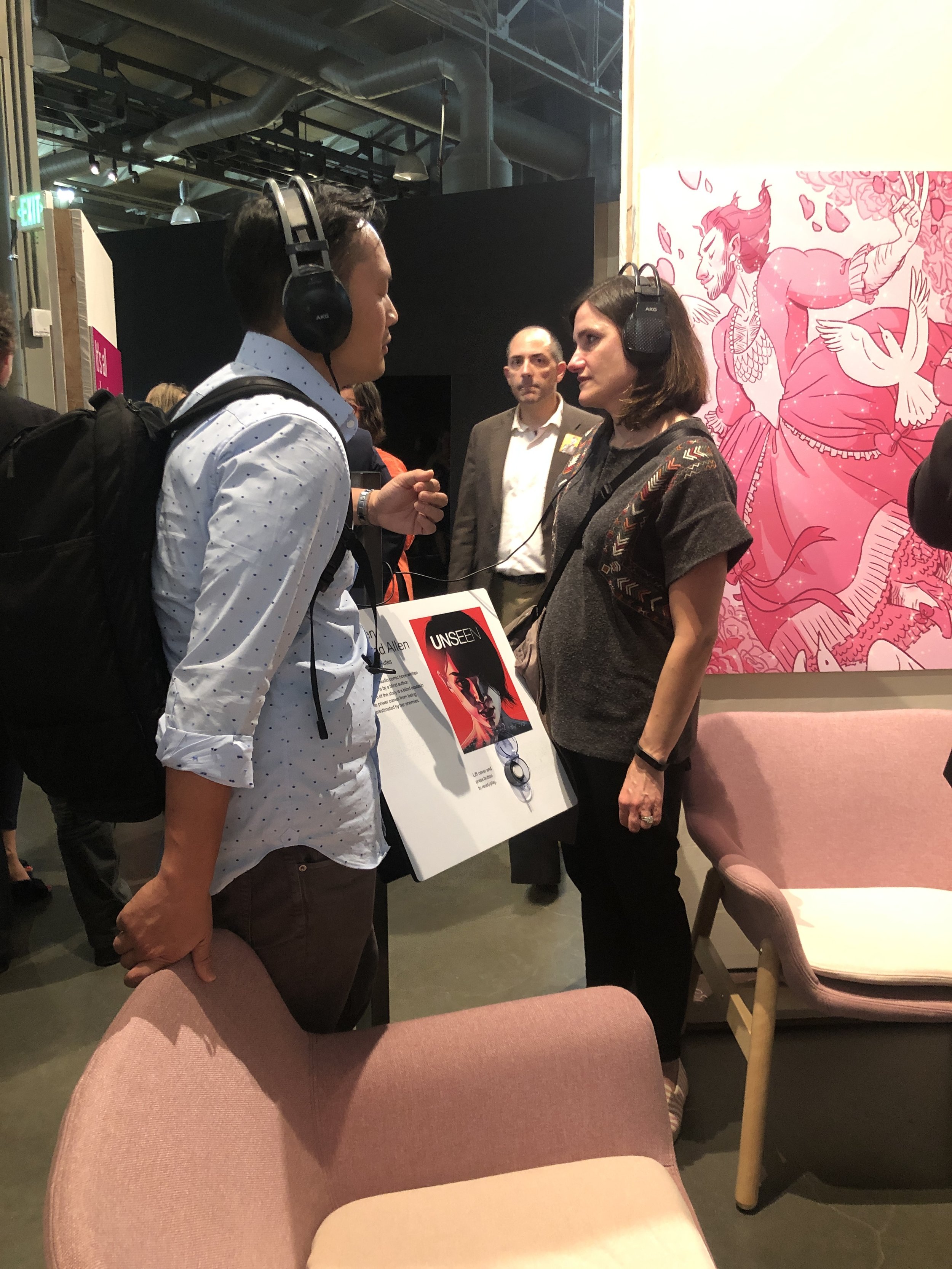 Two attendees listen to Unseen together at the exhibit.