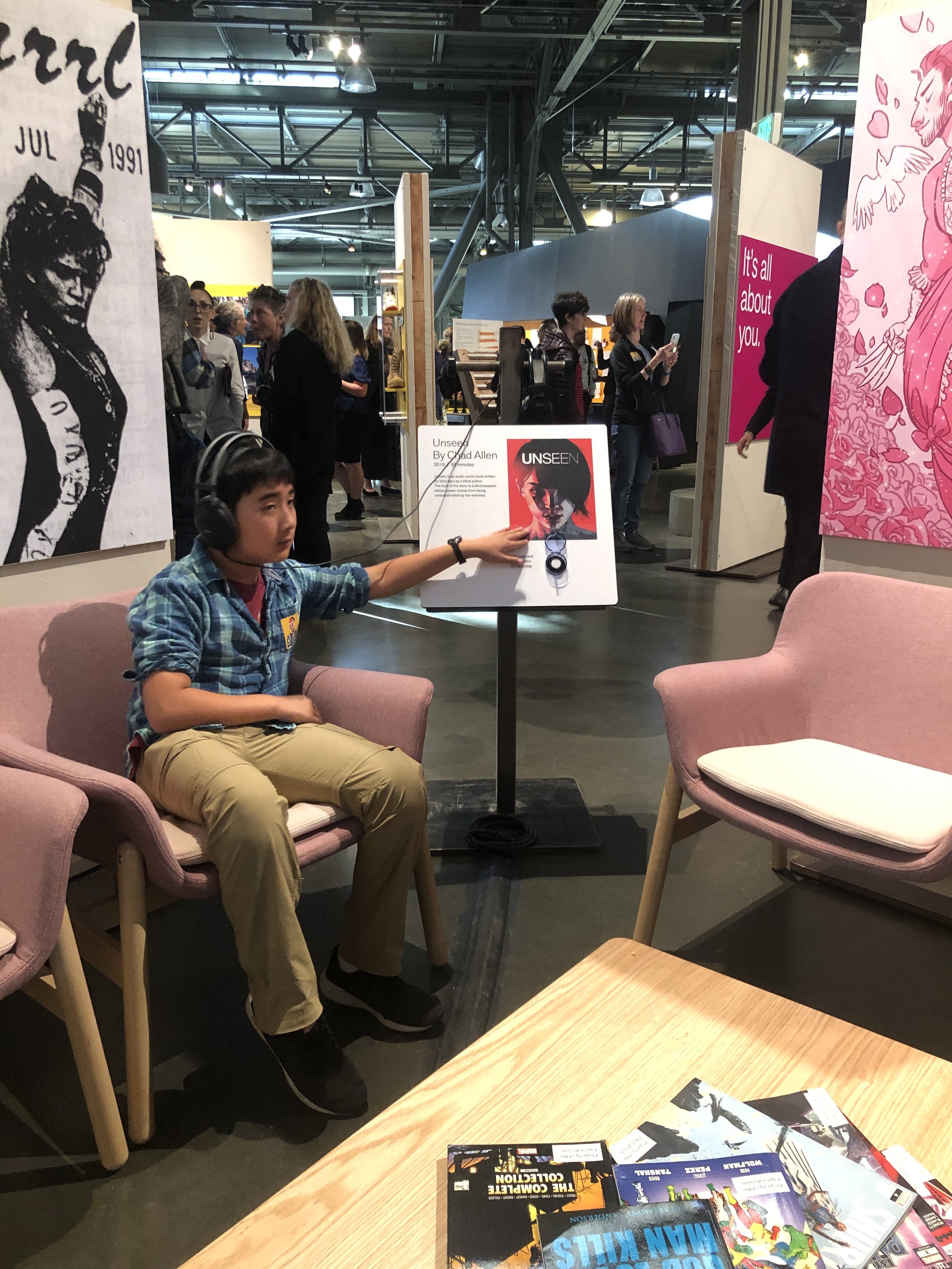 A teenager listening to Unseen at the exhibit and feeling the Braille description.