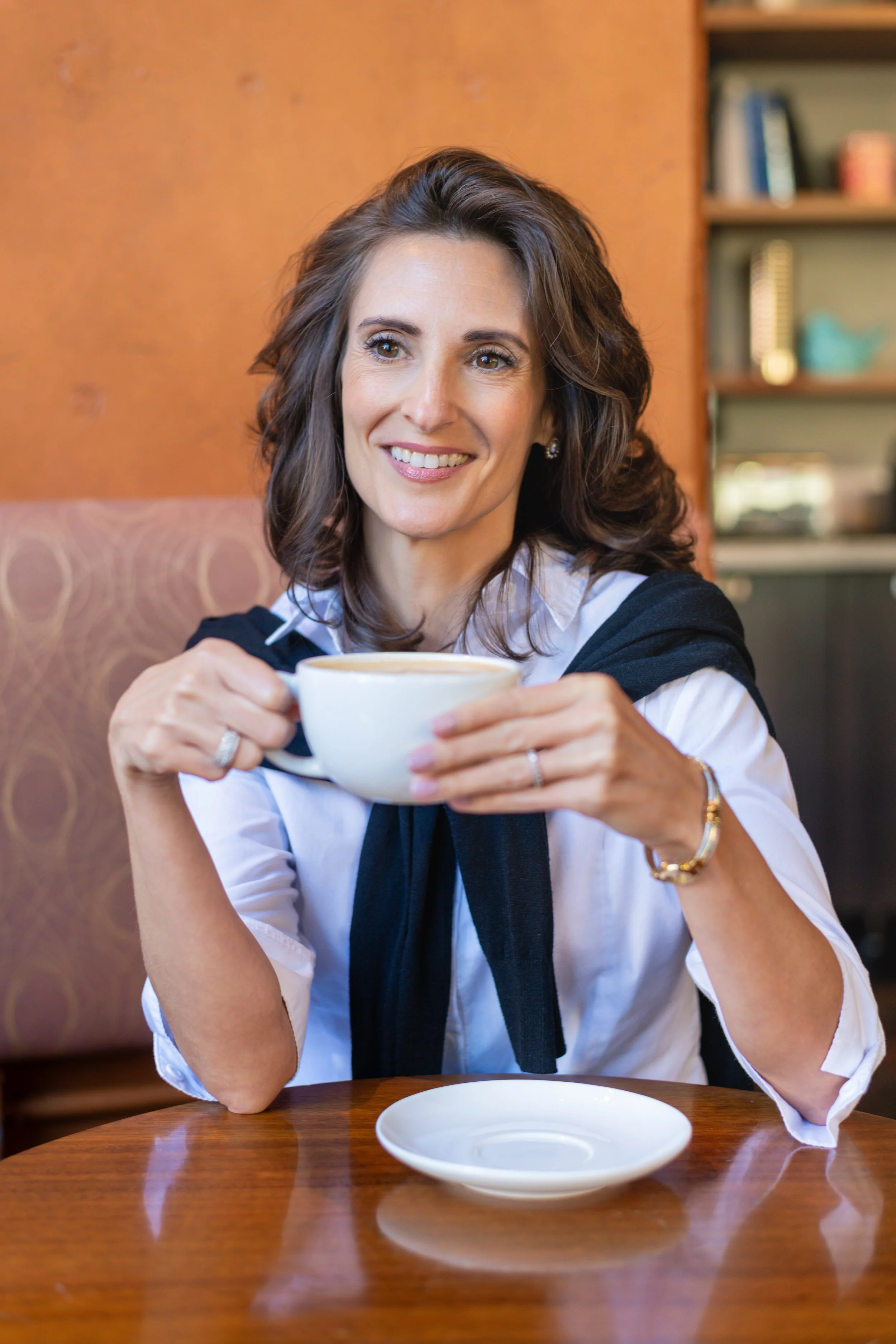 Woman smiling and holding a cup of coffee in a cafe.