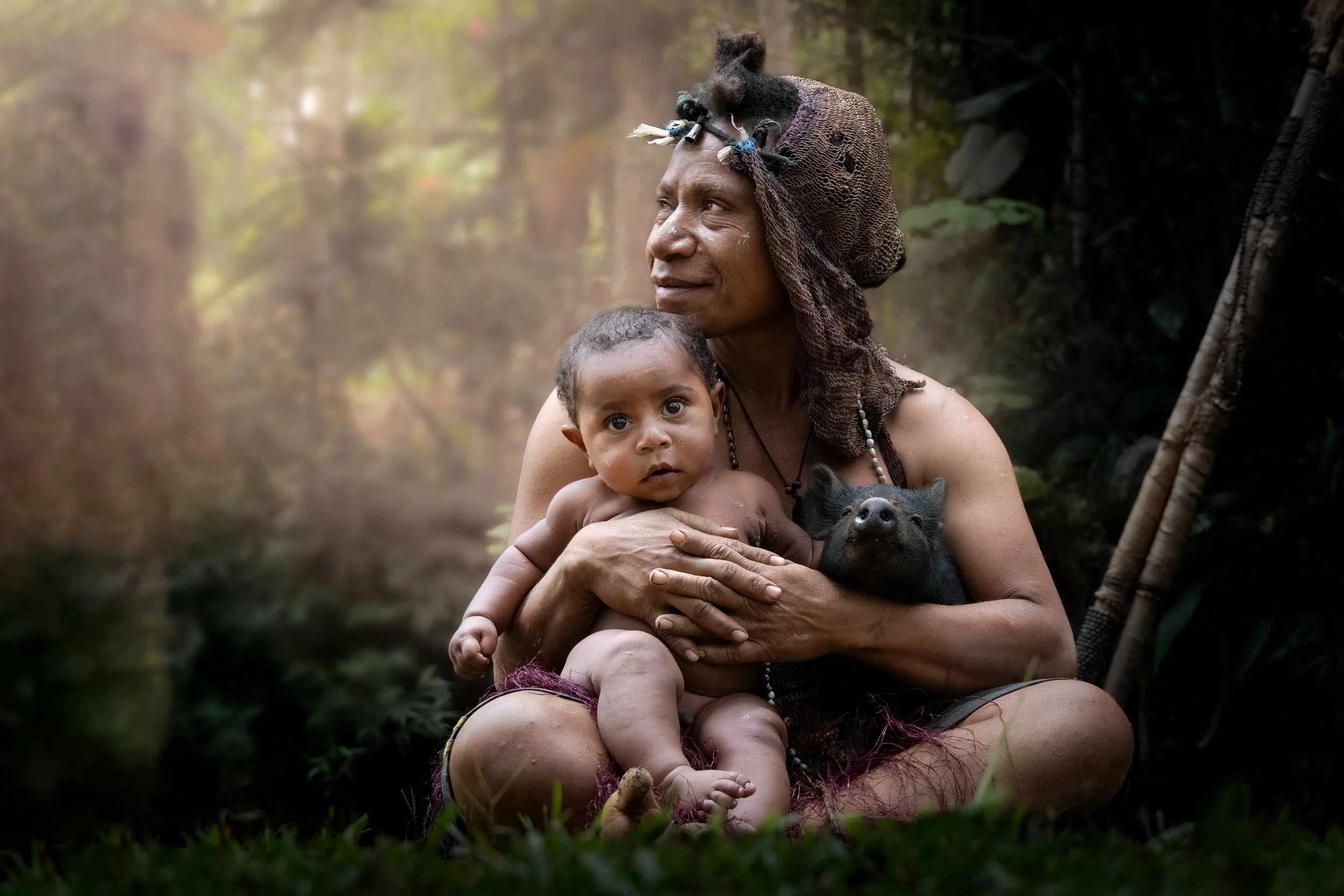 An indigenous woman holds her child and a small piglet in a rainforest setting, showcasing the documentary portrait opportunities available on a Papua New Guinea photo expedition.