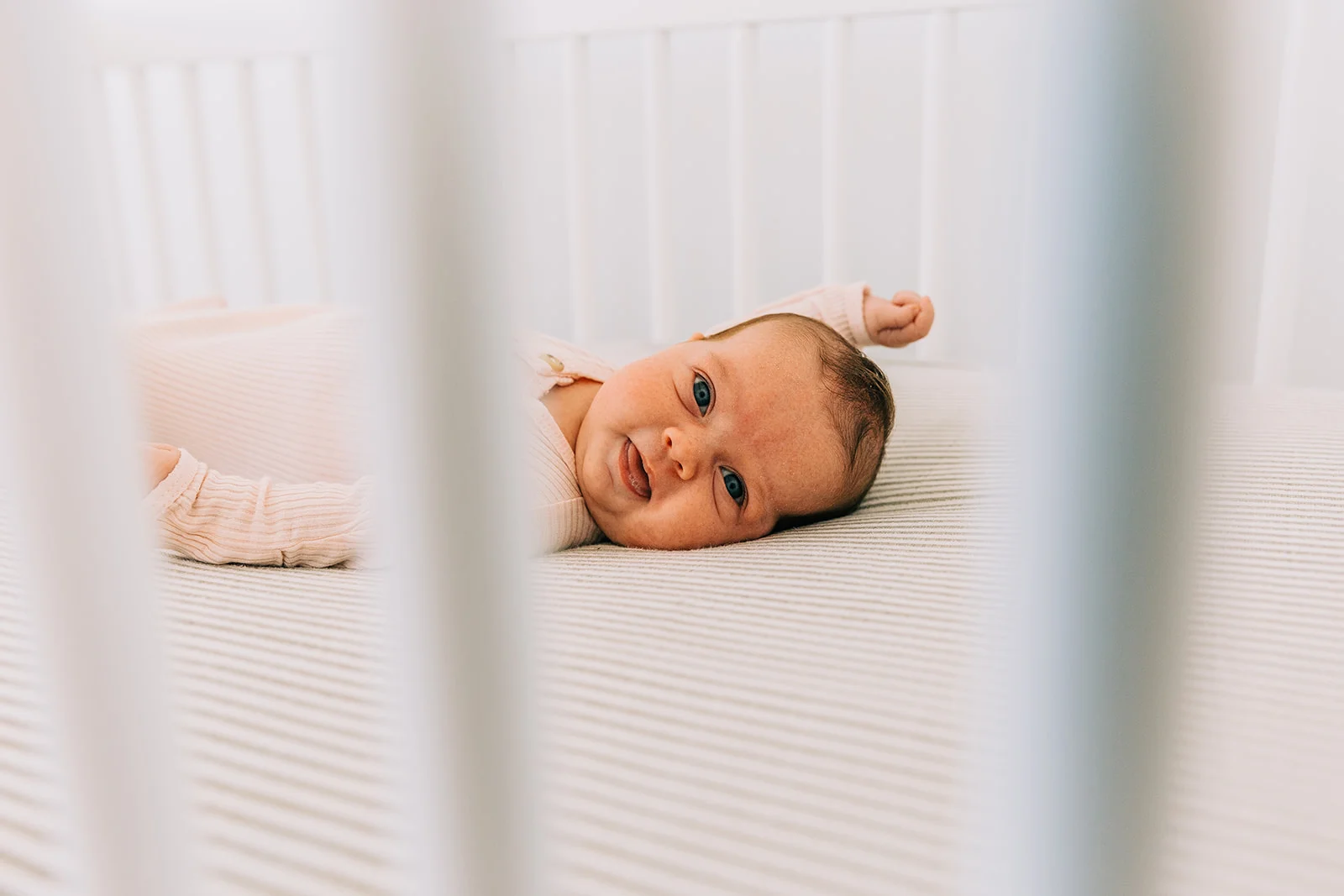 Bella Alder Photography captures this adorable shot of sweet baby girl Leighton through the crib during her newborn session at Blush Door Studio in Logan, Utah | #bellaalderphoto #newbornphotographer #utahnewbornphotos #babygirlphotos #babygirl #blushdoorstudio #newbornsession #utahbabies #babyphotoshoot #newborns