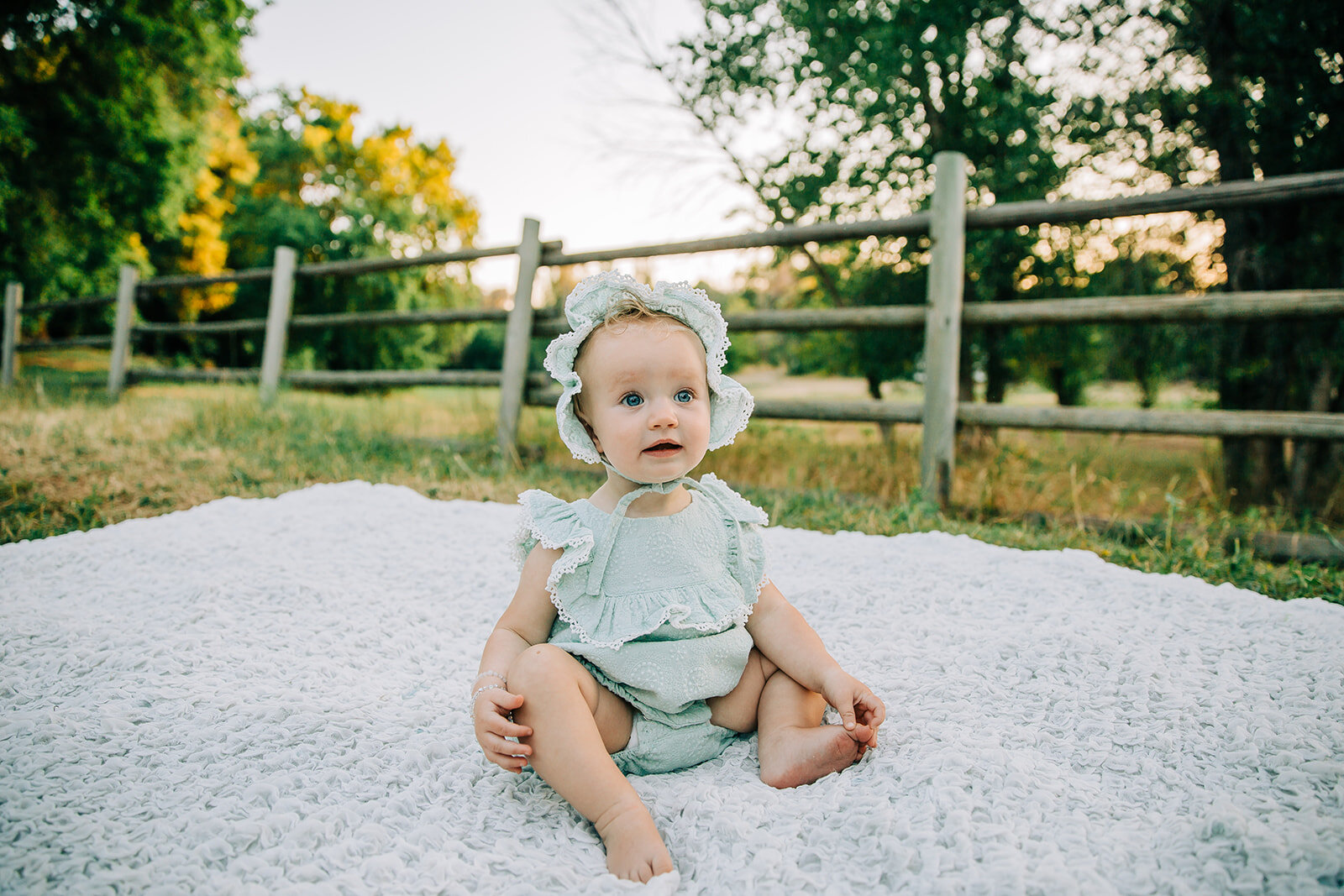  birthday photos first birthday kids photography cute baby outfits for girls playing with toes keeping kids attention baby hats girls fashion inspo baby photoshoot posing inspo sitting on a blanket posing ideas baby wearing bonnet Denzil Stewart park