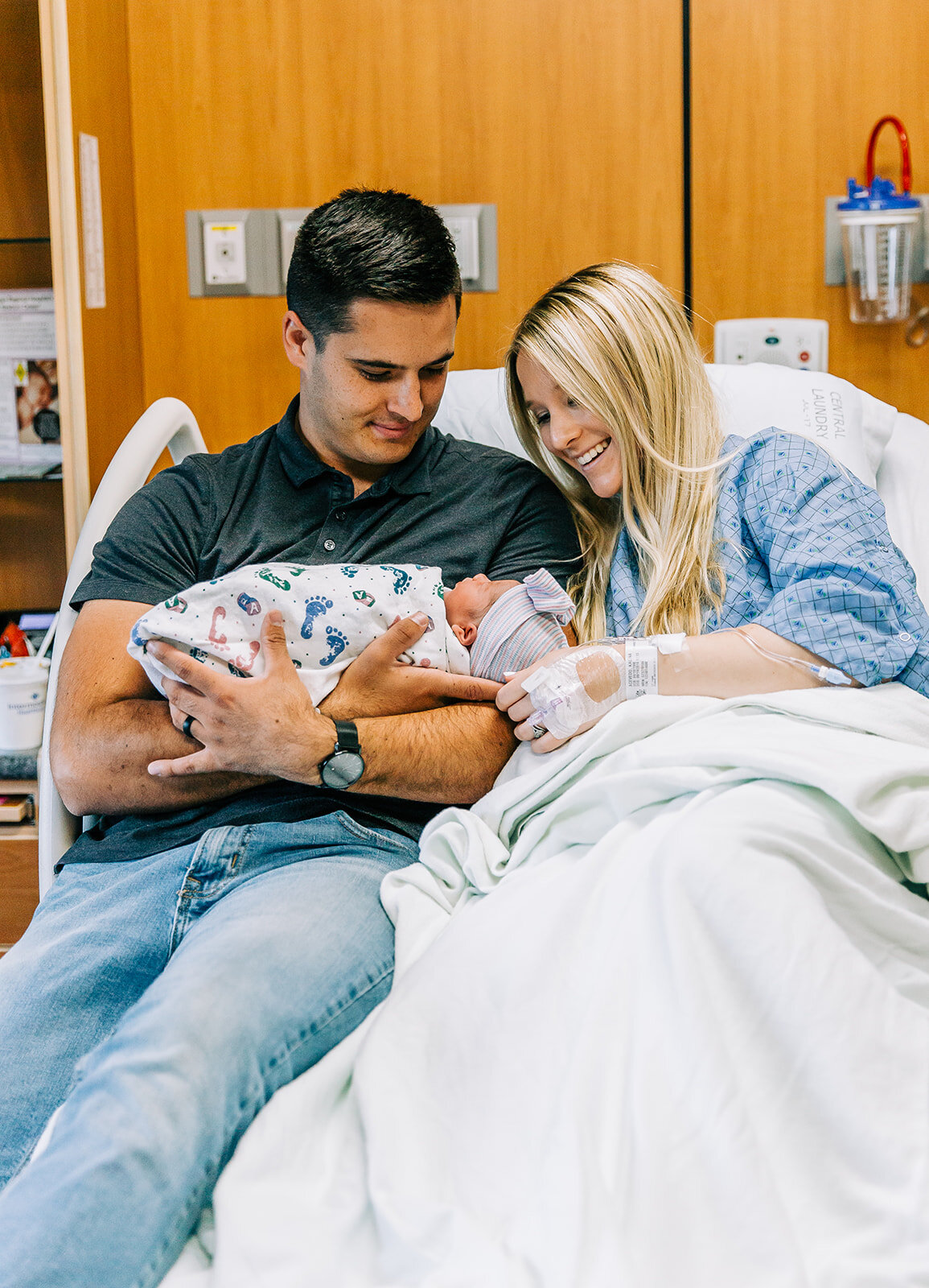  birth story photographer newborn baby family of three baby snuggles hospital birth delivery room photo inspo new mom and dad happy family birth story photo inspo family sitting in hospital bed unposed family photos Logan regional hospital newborn ph