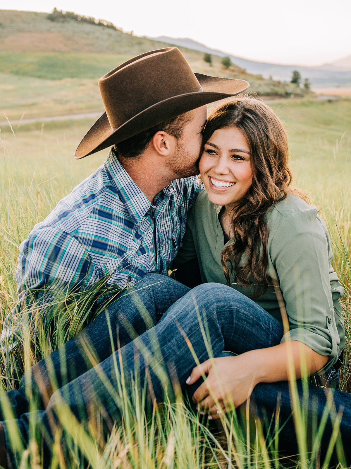  professional cache valley photographer grass hills and wildflowers couple posing ideas Utah engagement session paradise Utah farm boy and girl green field casual outfit ideas women hairstyles telling secrets lover swing dancing partners small town c