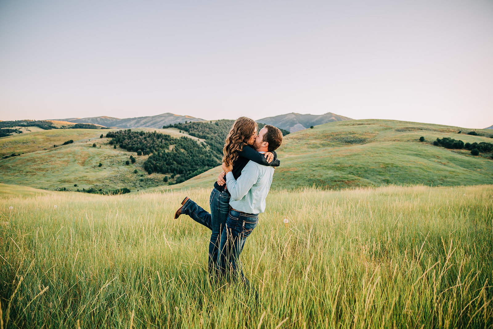  green hills and wildflowers kissing engagement pictures romantic moments foot popping cowboy boots country lovers small town love semi-formal engagement attire blue jeans summer time engagement session posing ideas couple posing ideas cache valley p