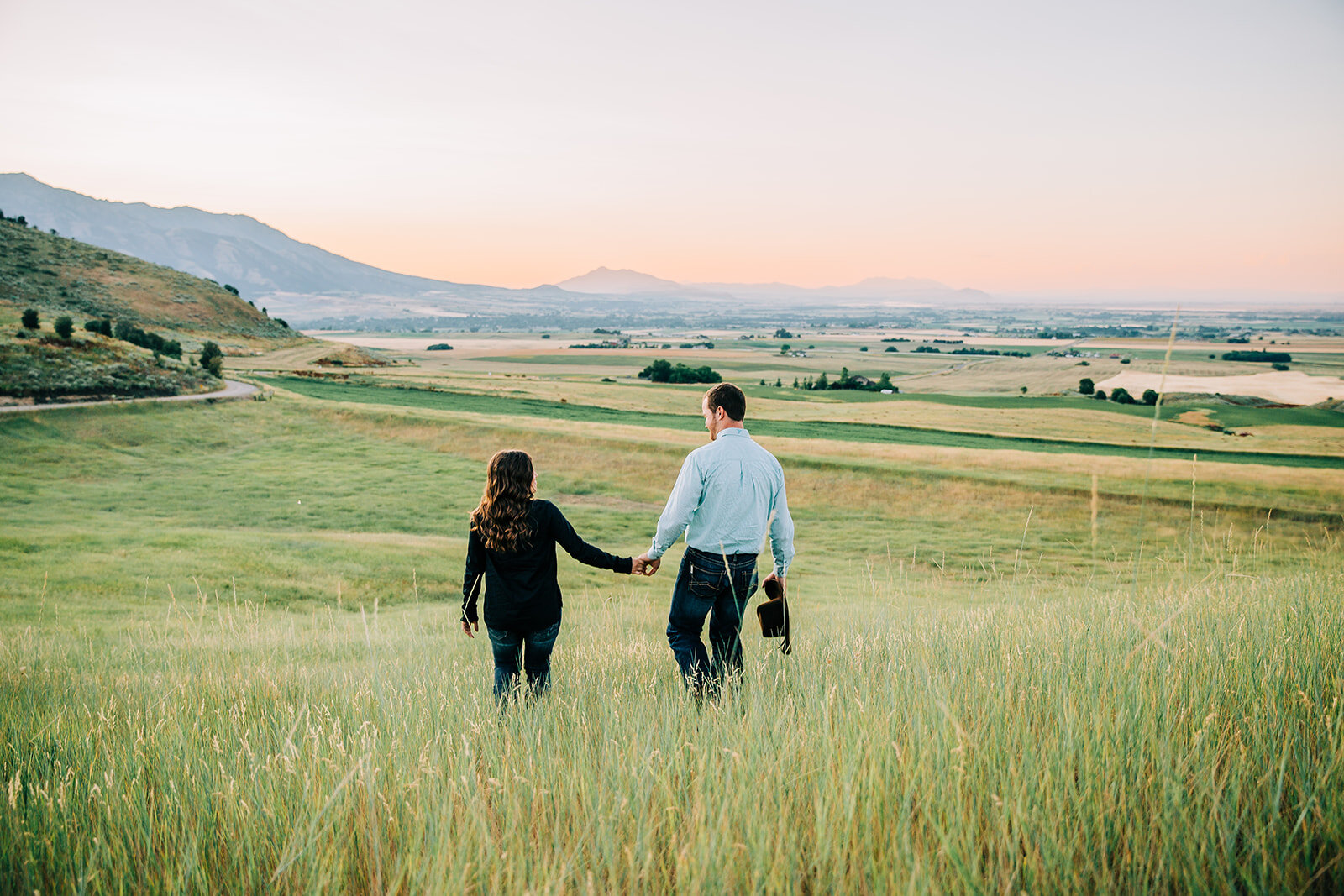  Utah engagement session walking and holding hands walking into the sunset summer time engagement beautiful couple romantic couple in love couple engagement outfit inspo mountain background paradise Utah country couple professional cache valley photo