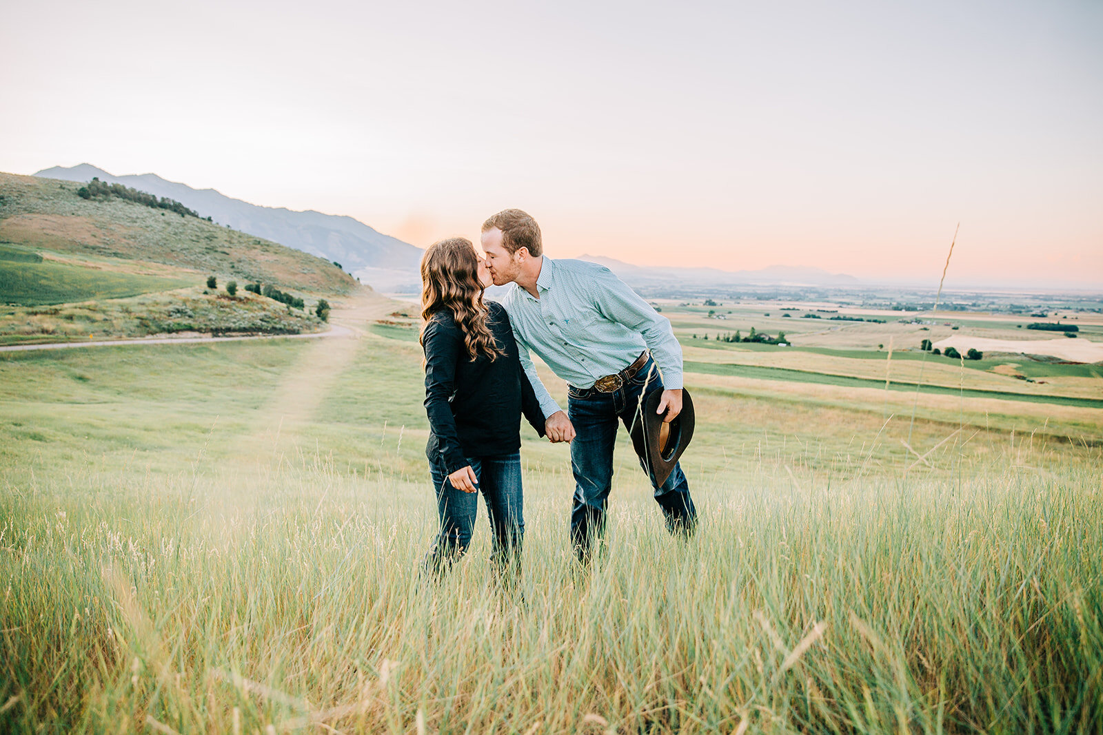  Engagement session sunset photography boyfriend girlfriend couple kissing posing inspo bride to be couple holding hands in grass field couple goals happy couple wildflowers country couple what to wear to engagements cache valley photographer paradis
