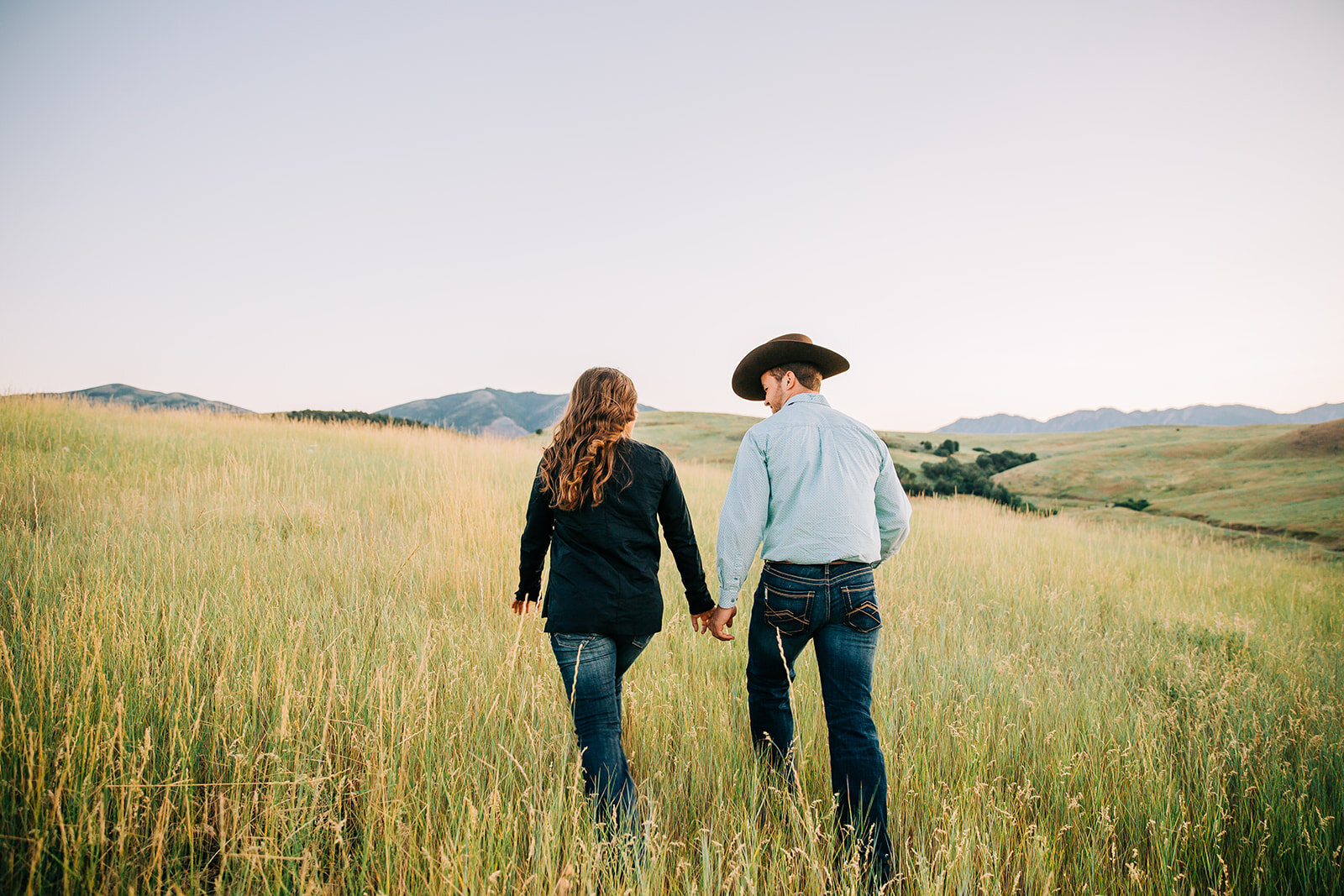  Utah photographer cache valley engagement session walking together grass and wildflowers long hair country lovers small town couple engagement outfit inspo summer time engagements couple posing inspo future mr and mrs paradise Utah couple session sw