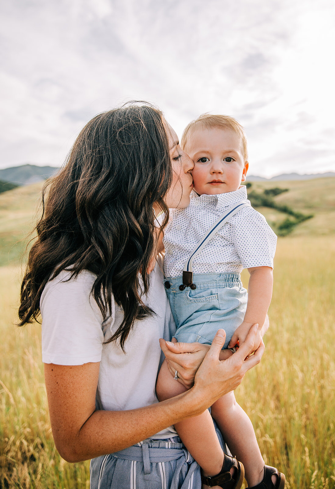  family pictures mom and baby boy shades of blue outfit coordination for family photos in summer logan utah family photographer bella alder photography blue suspenders baby boy mom kissing her baby boy mom and son posing together woman holding her ch