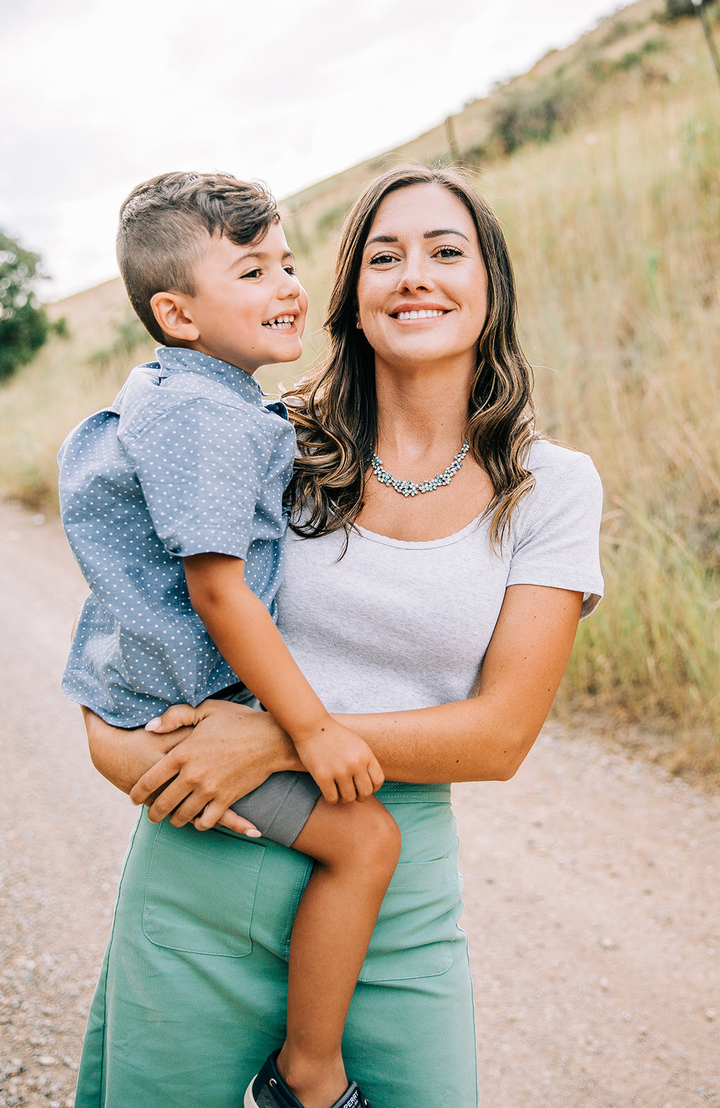 mom and son teal mint and blue family pictures outfit coordination brunette turquoise jewelry young boy mom holding her son yellow rolling hills in paradise utah professional family pictures family photo time smile for the camera say cheese utah fam