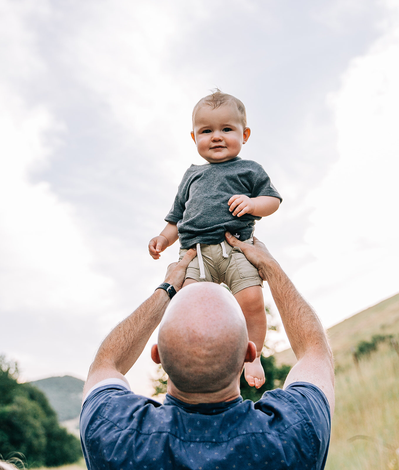  young boy baby boy outfit ideas for summer family photos classy cute outfits grey shirt dad holding baby boy up in the air cute photo of baby during family pictures flying baby up in the sky small family portraits paradise utah bella alder photograp