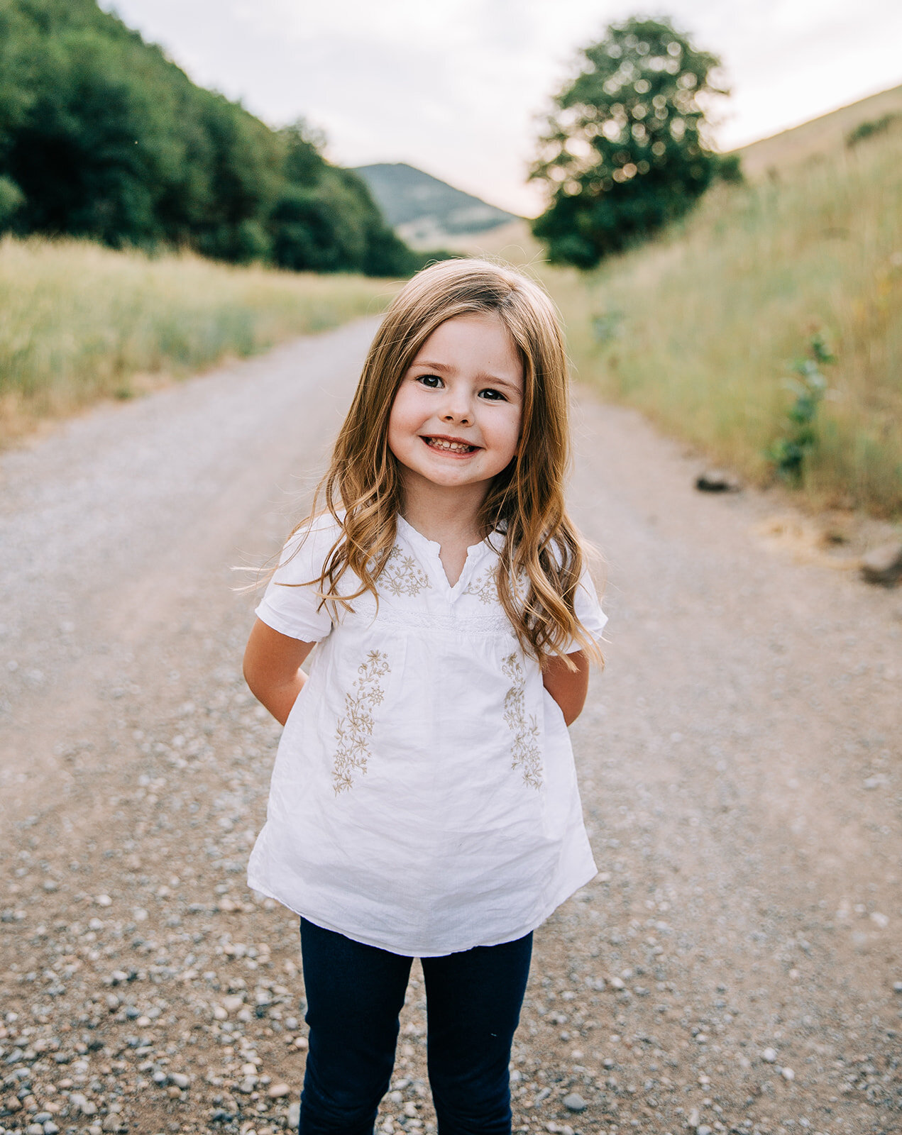  young girl white shirt curly brunette child individual portraits during extended family session in hyrum utah bella alder photography cache valley family photographer available for travel throughout utah family pictures daughter outfit idea for clas