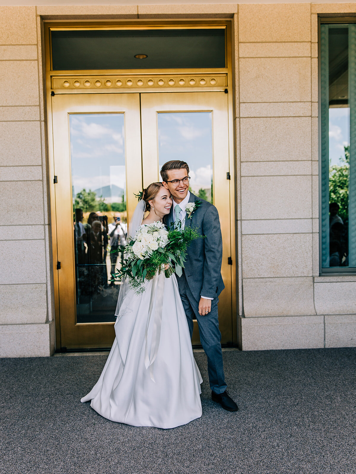  bride and groom hugging posing for a picture after leaving the oquirrh mountain temple in south jordan utah after their sealing ceremony just married weddings in salt lake city utah wedding photographer available for travel gold door modest wedding 