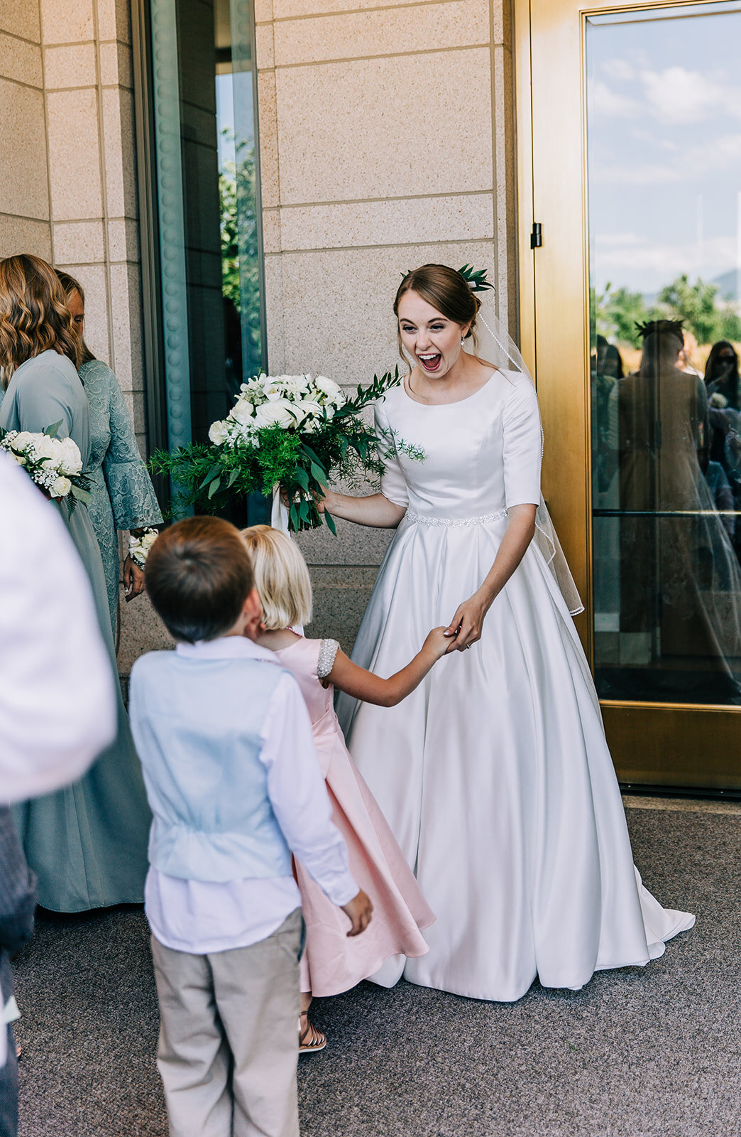  bride holding white floral bouquet wedding bouquet inspiration white and green flowers kids greeting the bride elbow-length sleeves wedding gown affordable wedding photographer salt lake city brides utah couples mormon brides lds wedding oquirrh mou