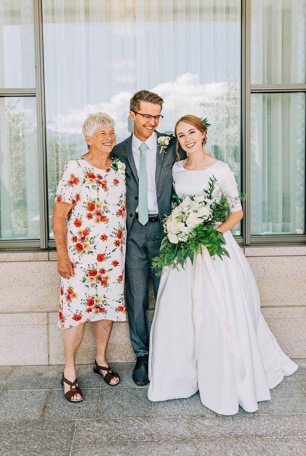  bride and groom posing with family for family pictures after the wedding ceremony in the oquirrh mountain lds temple south jordan utah professional wedding day photography pictures outside the temple with friends and family modest wedding gown elbow