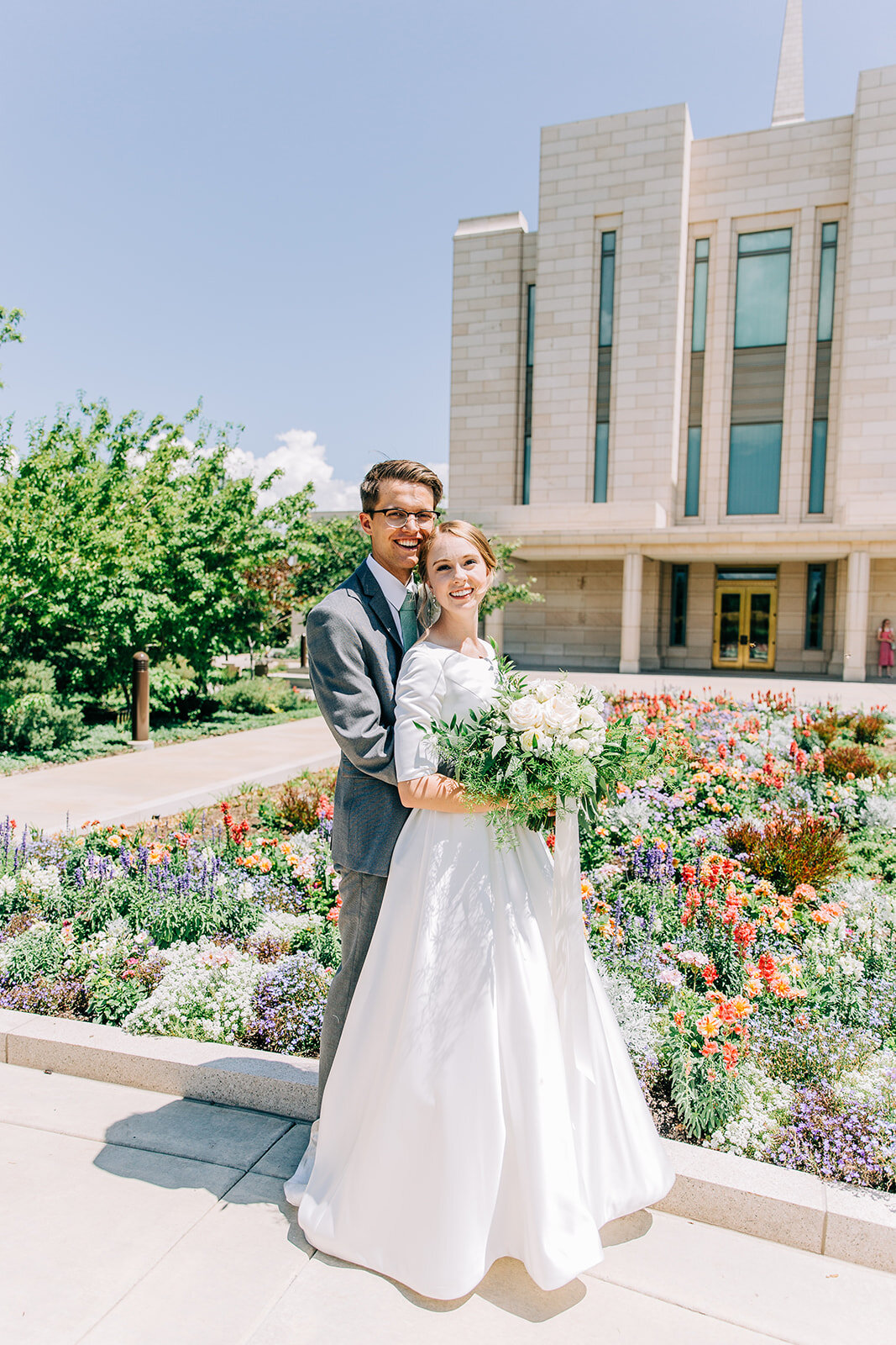  bride and groom picture with the oquirrh mountain temple in the background after lds sealing ceremony summer wedding florals happy couple husband and wife newlyweds after their salt lake city utah wedding affordable wedding photographer bella alder 
