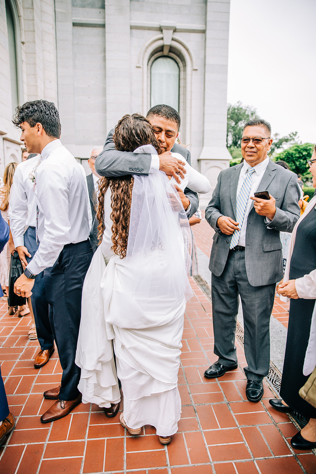  salt lake city wedding bride hugging her father outside the salt lake city lds temple square professional utah wedding photographer temple exit friends and family at wedding long veil lds couple lds bride bella alder photography wedding photographer