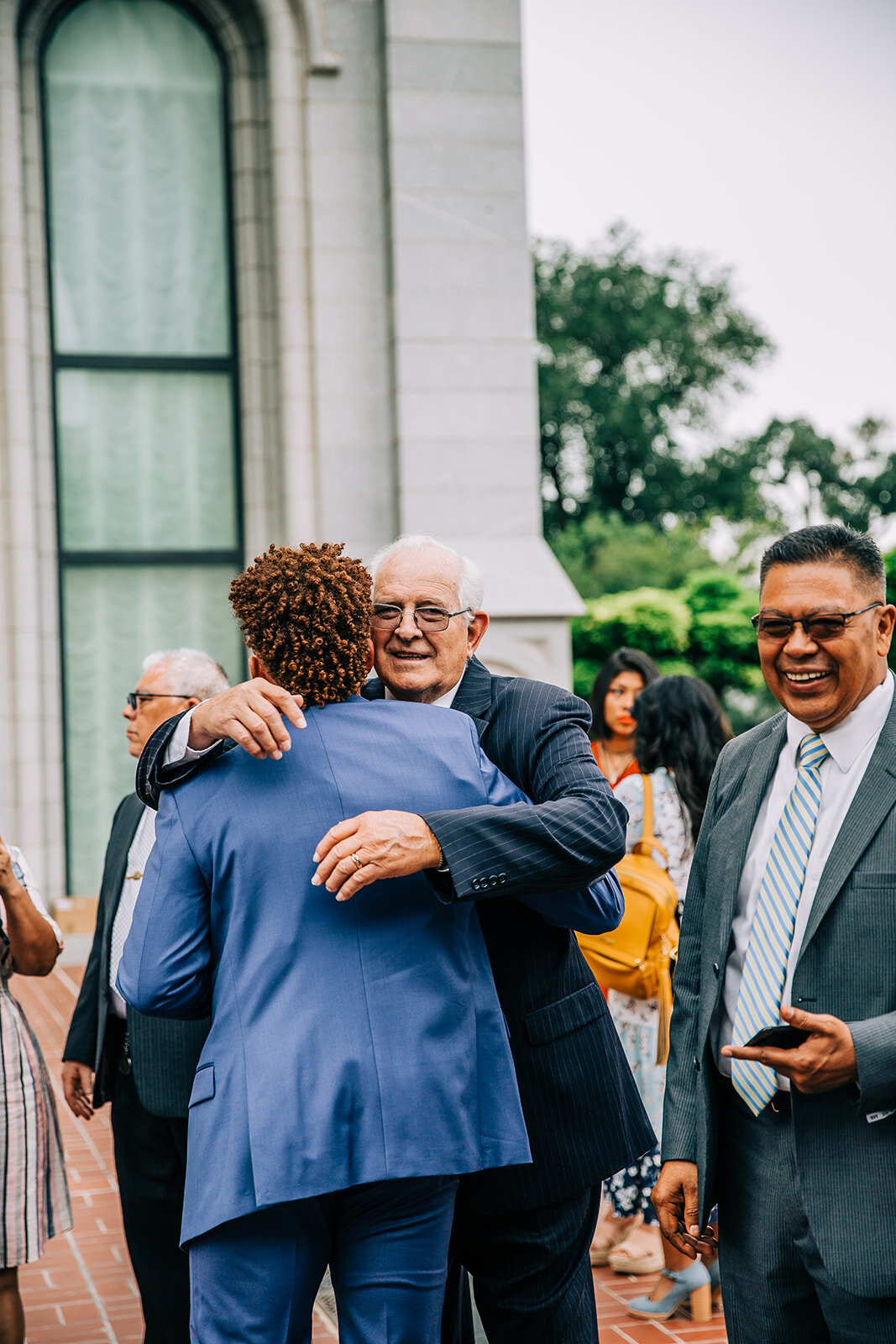  groom hugging his grandpa outside the temple after his wedding ceremony salt lake city utah wedding photographer pictures from the wedding day groom blue suit affordable wedding photos professional photographer bella alder photography groom style in