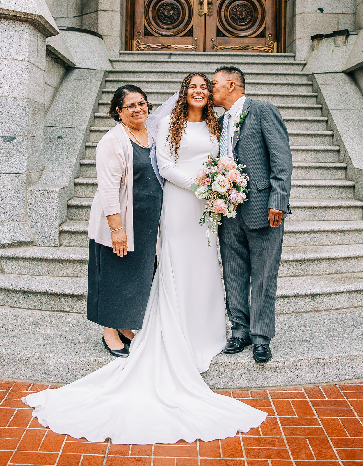  the bride with her parents on her wedding day outside the salt lake city lds temple steps family pictures after temple sealing lds bride professional wedding day photography by bella alder wedding photos you’ll cherish timeless wedding style bridal 