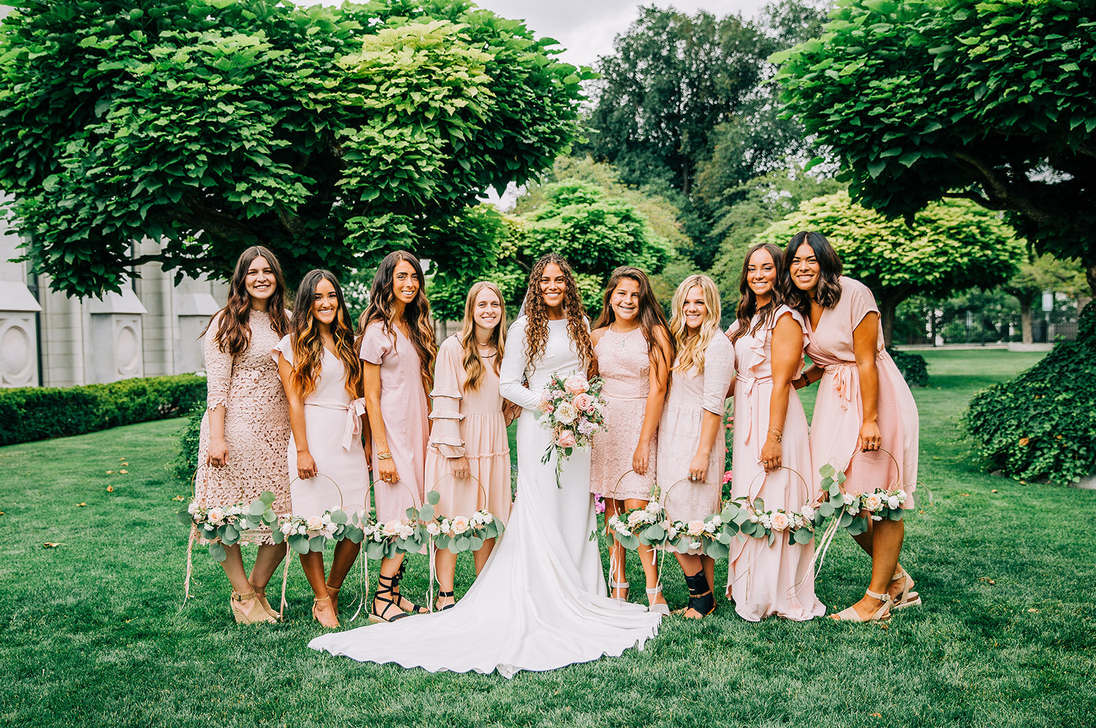  wedding party photo with just the girls bridesmaids with bride outside the temple square friends and family shots after sealing ceremony at salt lake city utah lds temple bride with her girls girl gang best friends blush bridesmaid dresses light pin