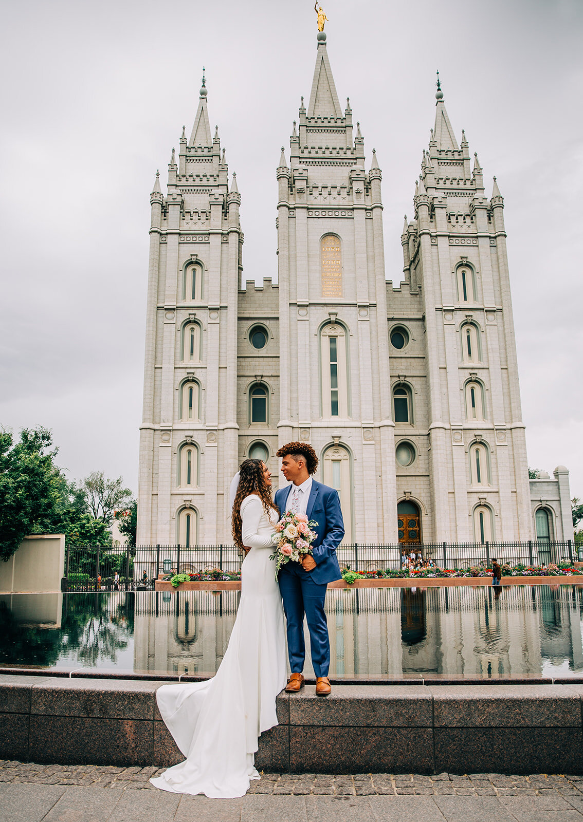  salt lake city temple beautiful shot of couple kissing on the fountain in front of the temple long wedding gown train wedding pose idea for bride and groom married in the salt lake city lds temple temple square fountains adorable newlyweds bridals p
