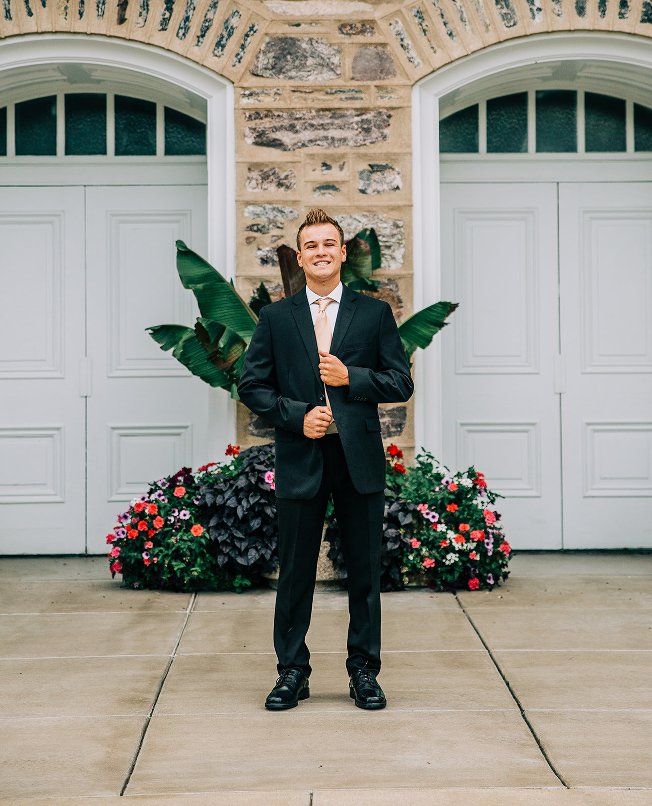  young man standing tall male model logan utah temple professional photographer in logan utah cache valley missionary photographer black suit young elder called to serve missionary training center mormon missionary holding the front of his suit missi