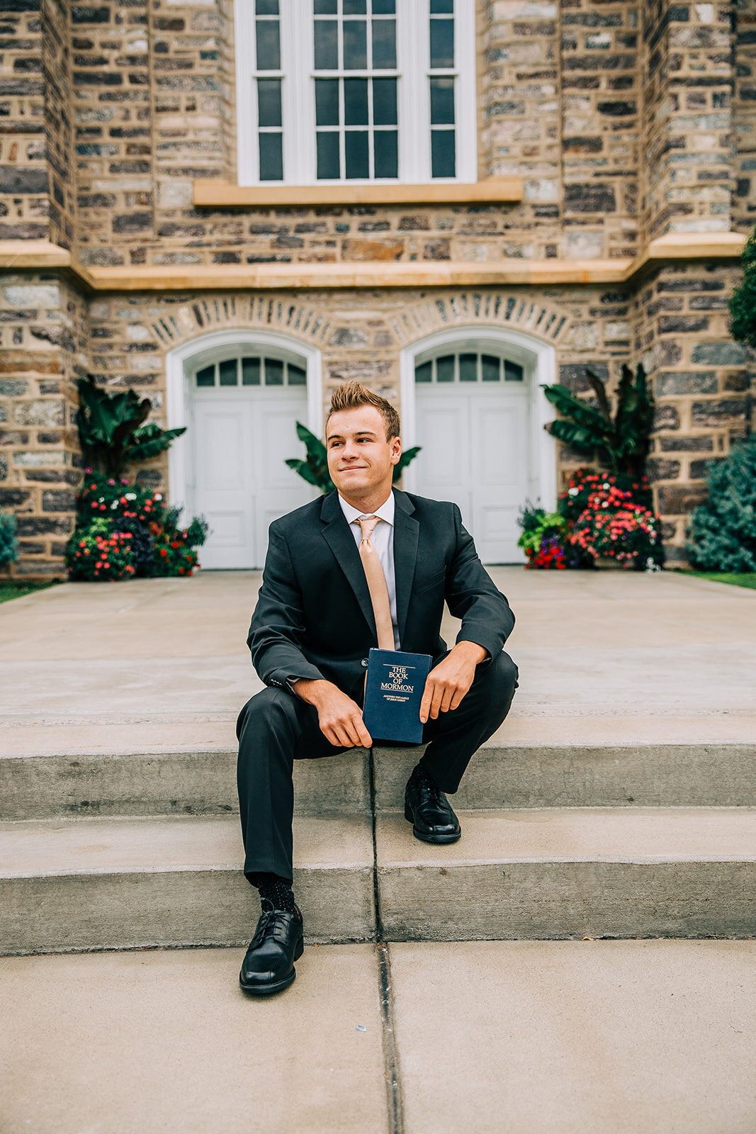  young man sitting on the steps missionary pose book of mormon young elder about to enter the mtc missionary training center holding the book of mormon outside the logan utah lds temple professional headshots missionary portraits cache valley utah #b