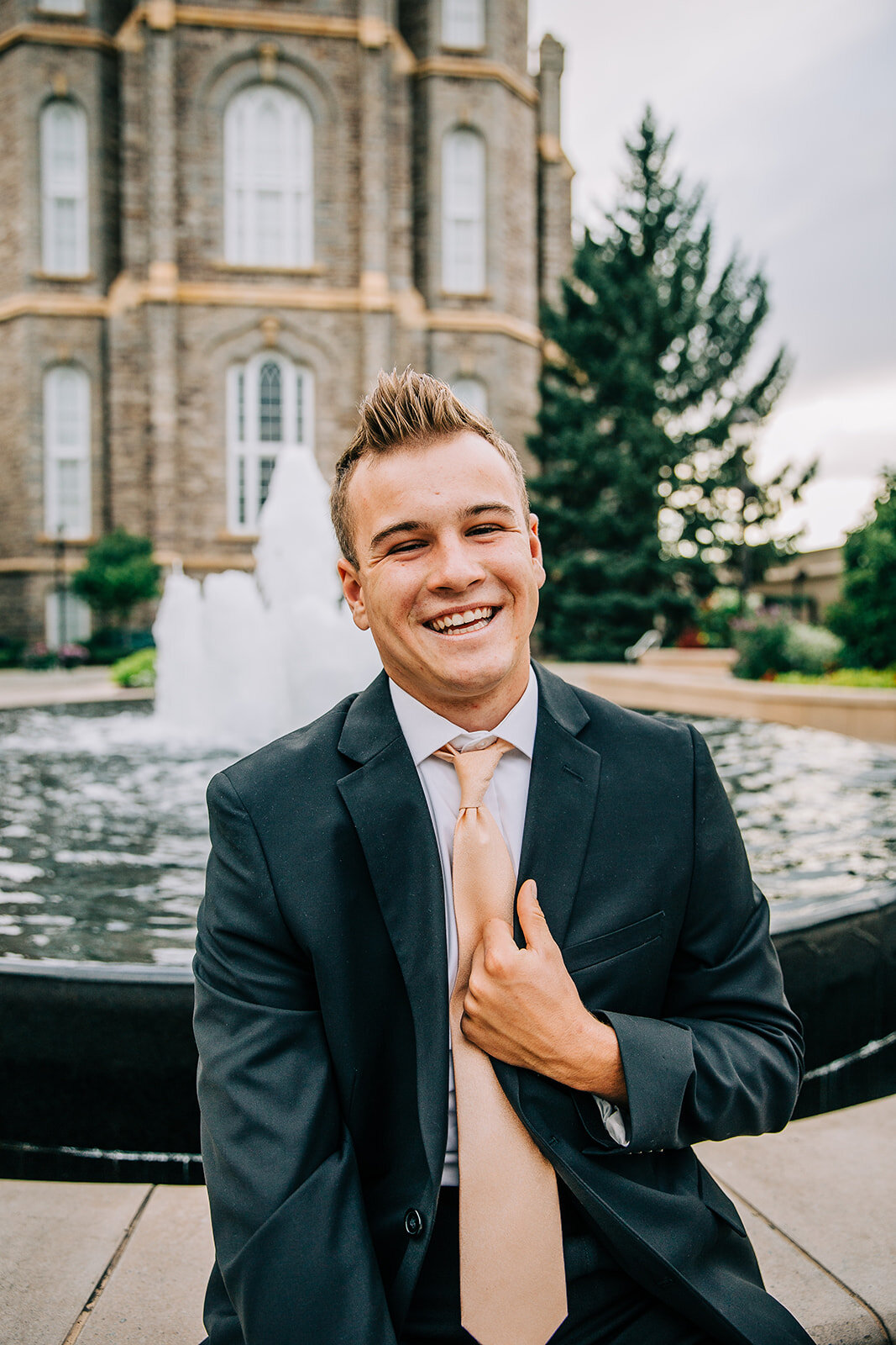  young man missionary called to serve elder holding his suit peach tie posing in front of the fountain at the logan utah temple lds missionary I hope they call me on a mission las vegas nevada missionary photos #bellaalderphoto #missionary #missionar