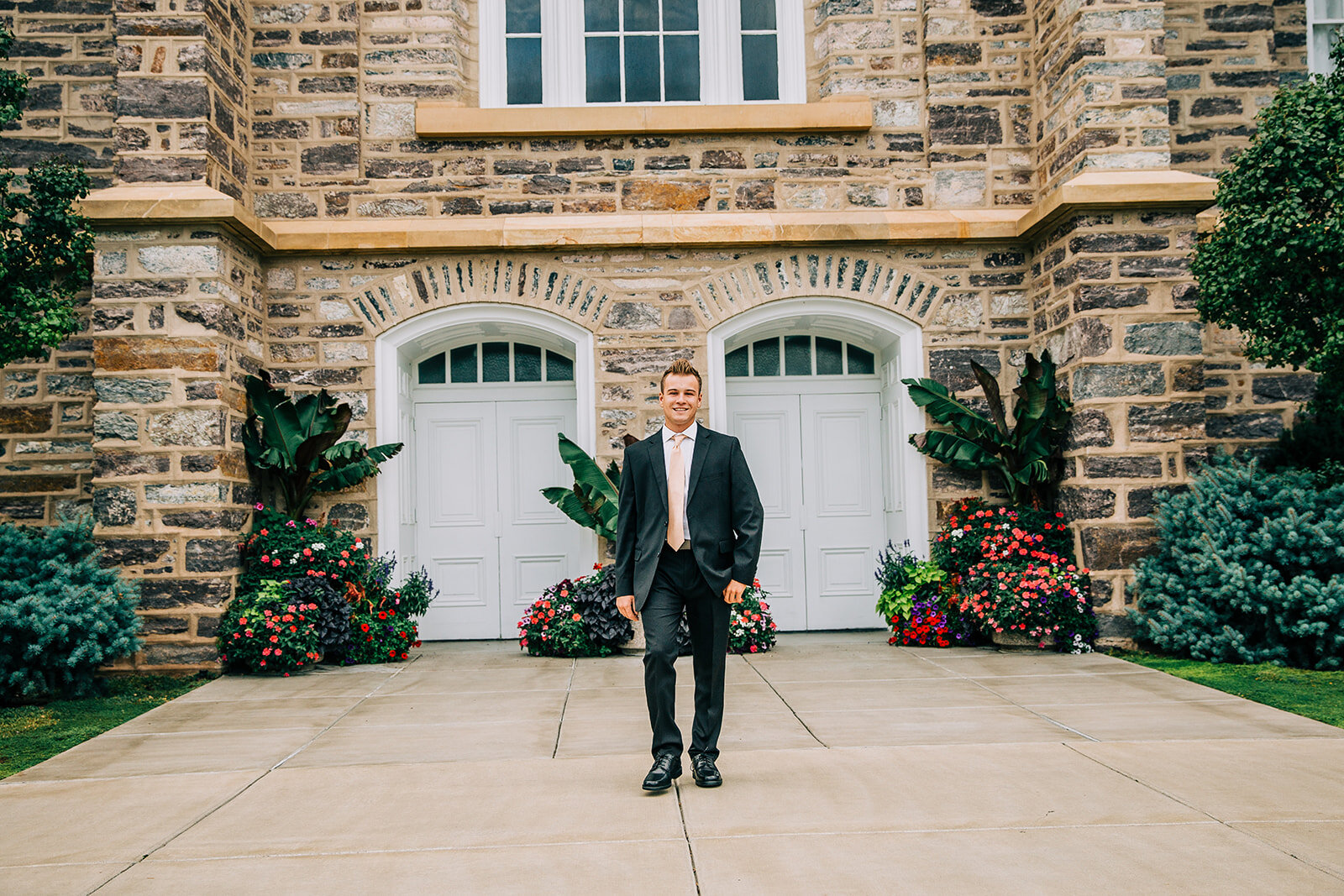  missionary in a black suit and peach tie at the logan utah temple stone and brick building young man posing hand in pocket missionary photo pose ideas professional senior portraits classy senior session bella alder photography cache valley #bellaald