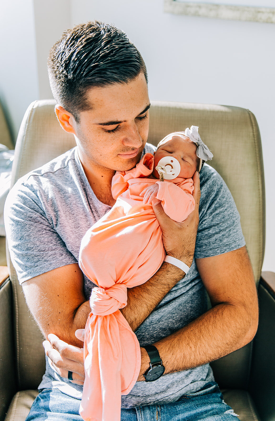  birth story picture of baby girl with a binky in her mouth pink swaddle picture with daddy first time dad hospital fresh 48 session after the baby is born it’s a girl baby girl with grey headband bow darling pose for newborn photography bella alder 