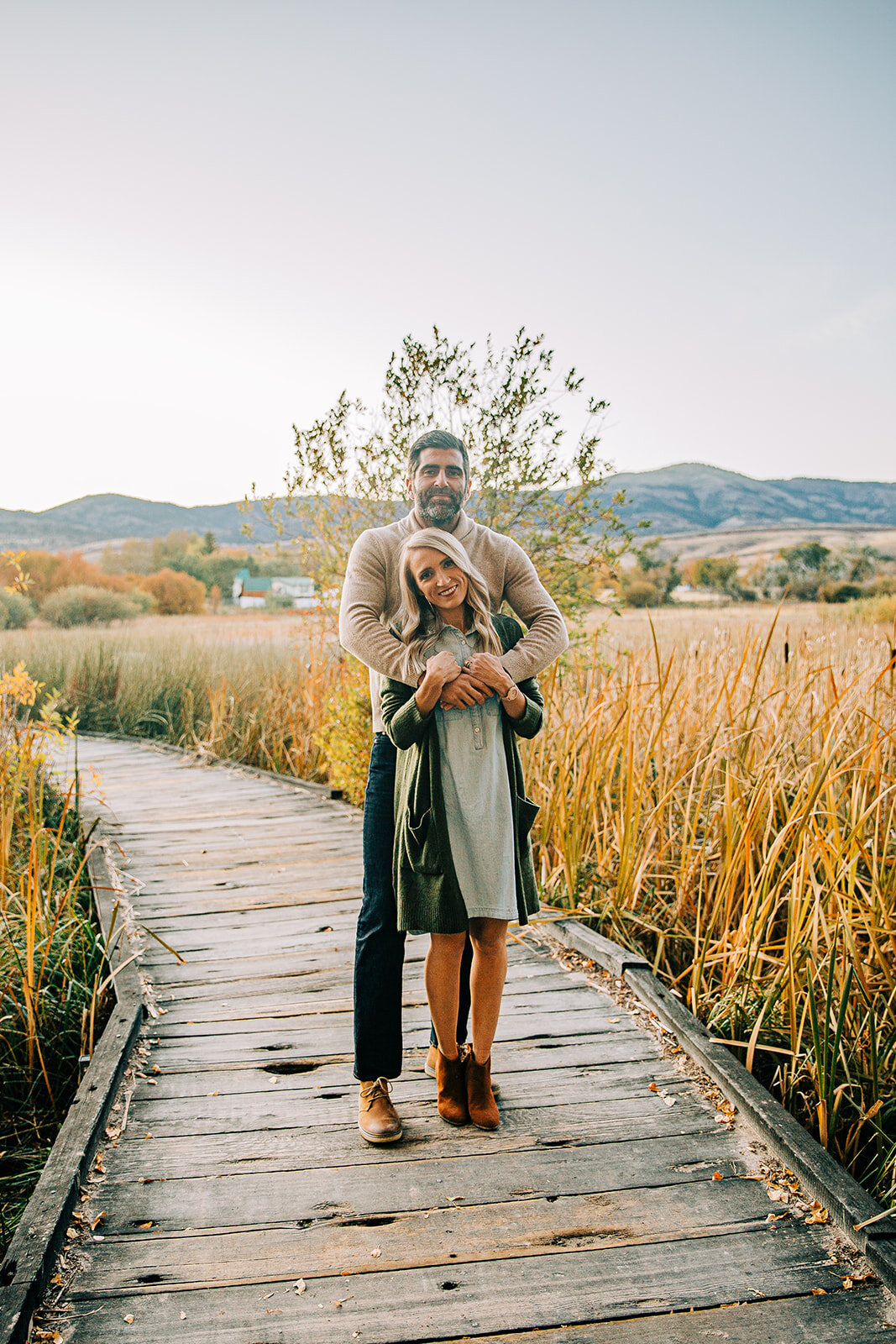  family of two man hugging woman from behind and smiling family pictures garden city park bear lake utah together again fields of gold mountains lakeside photos professional photographers in utah utah family photographers extended family siblings fam