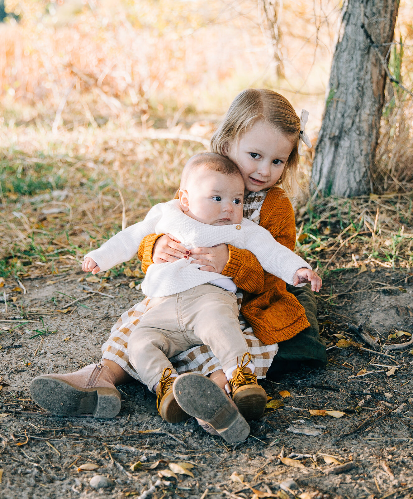  big sister holding baby sibling sitting on the ground childrens fashion family pictures garden city park bear lake utah together again fields of gold mountains lakeside photos professional photographers in utah utah family photographers extended fam