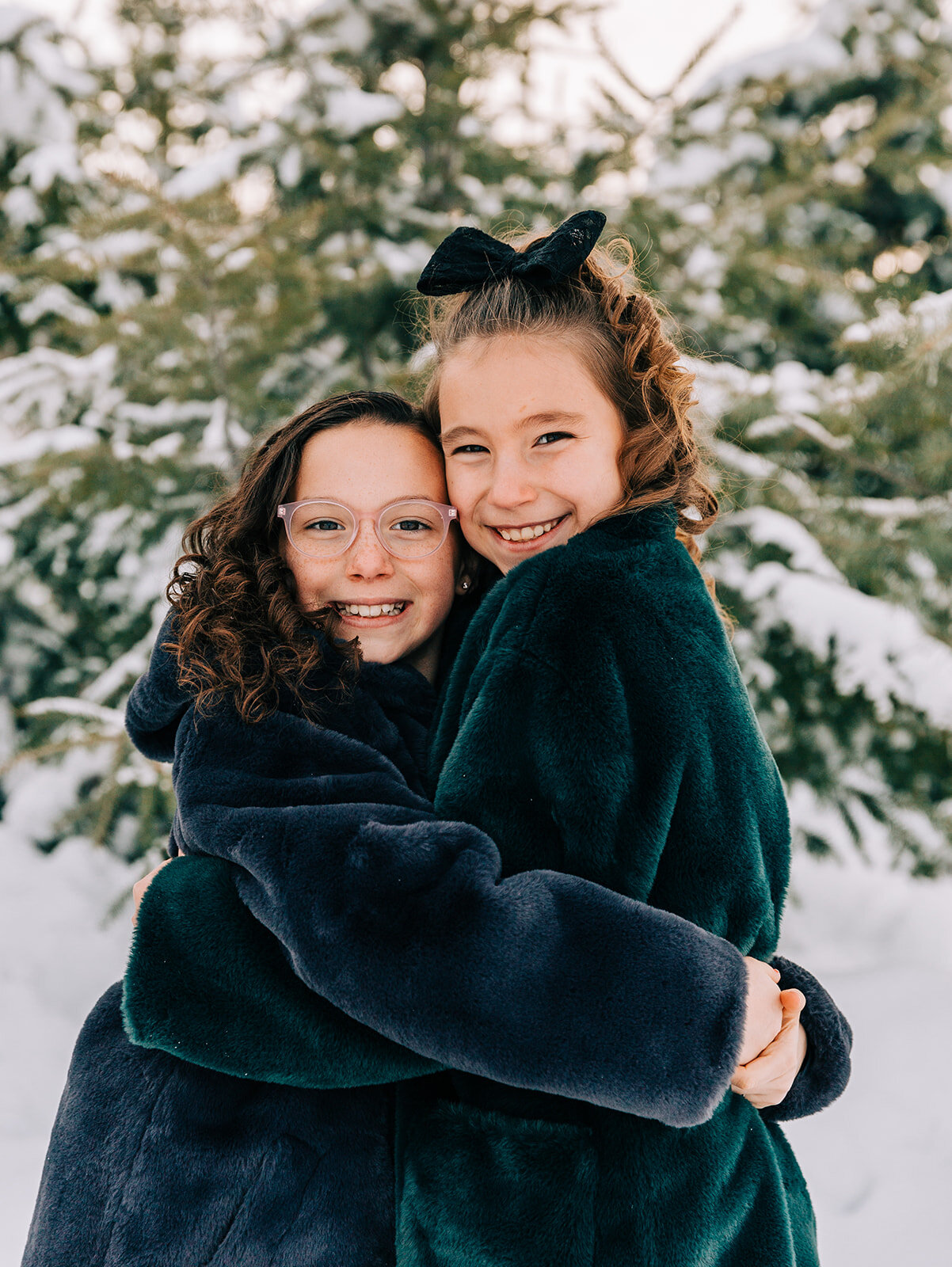  sisters in fuzzy coats hugging sister love best friends glasses winter fashion family pictures daughters family picture styling inspiration family pose ideas winter photoshoot snowy pictures adams acres tree farm family photographers in utah profess