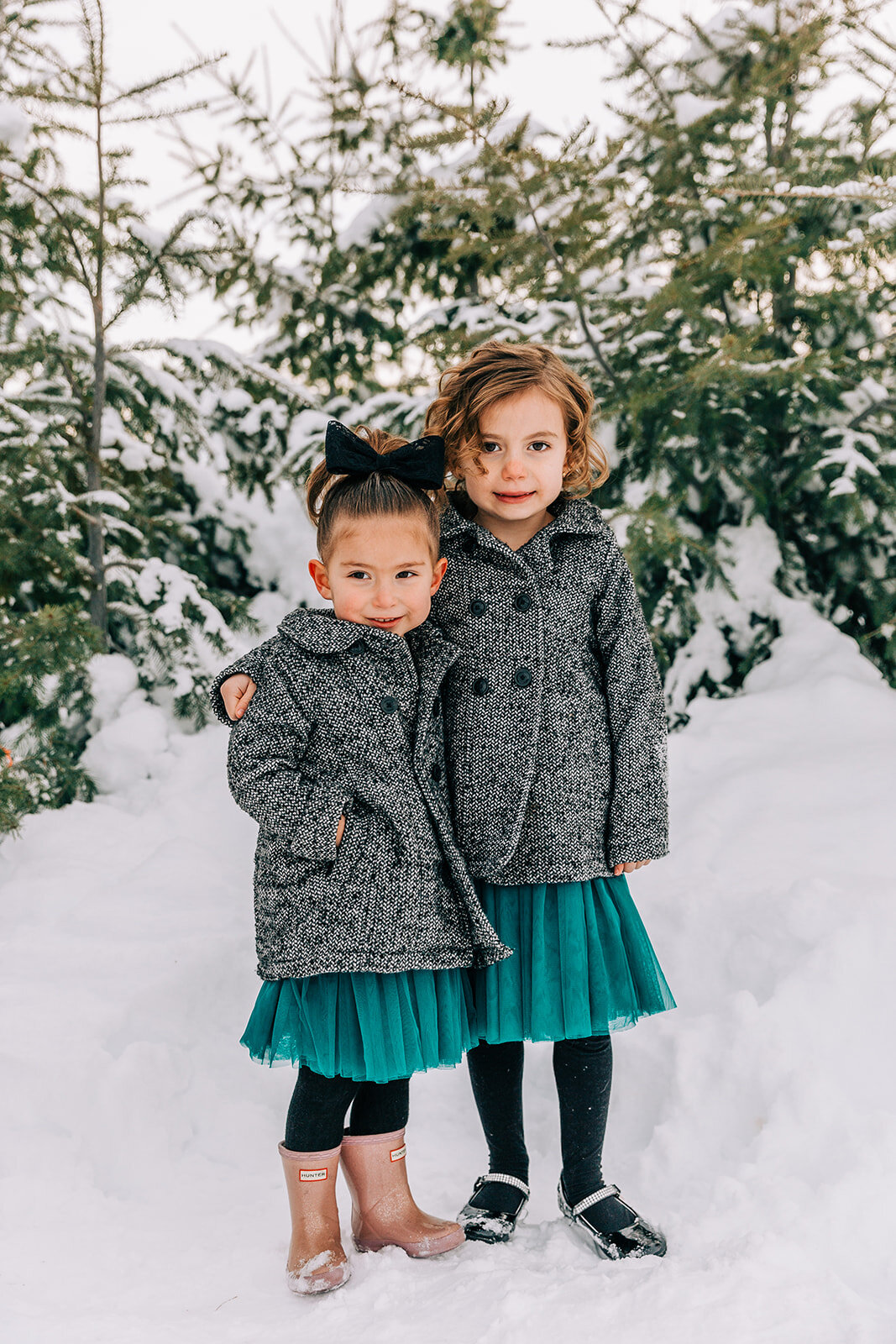  sisters in matching coats hugs sister love best friends glasses winter fashion family pictures daughters family picture styling inspiration family pose ideas winter photoshoot snowy pictures adams acres tree farm family photographers in utah profess