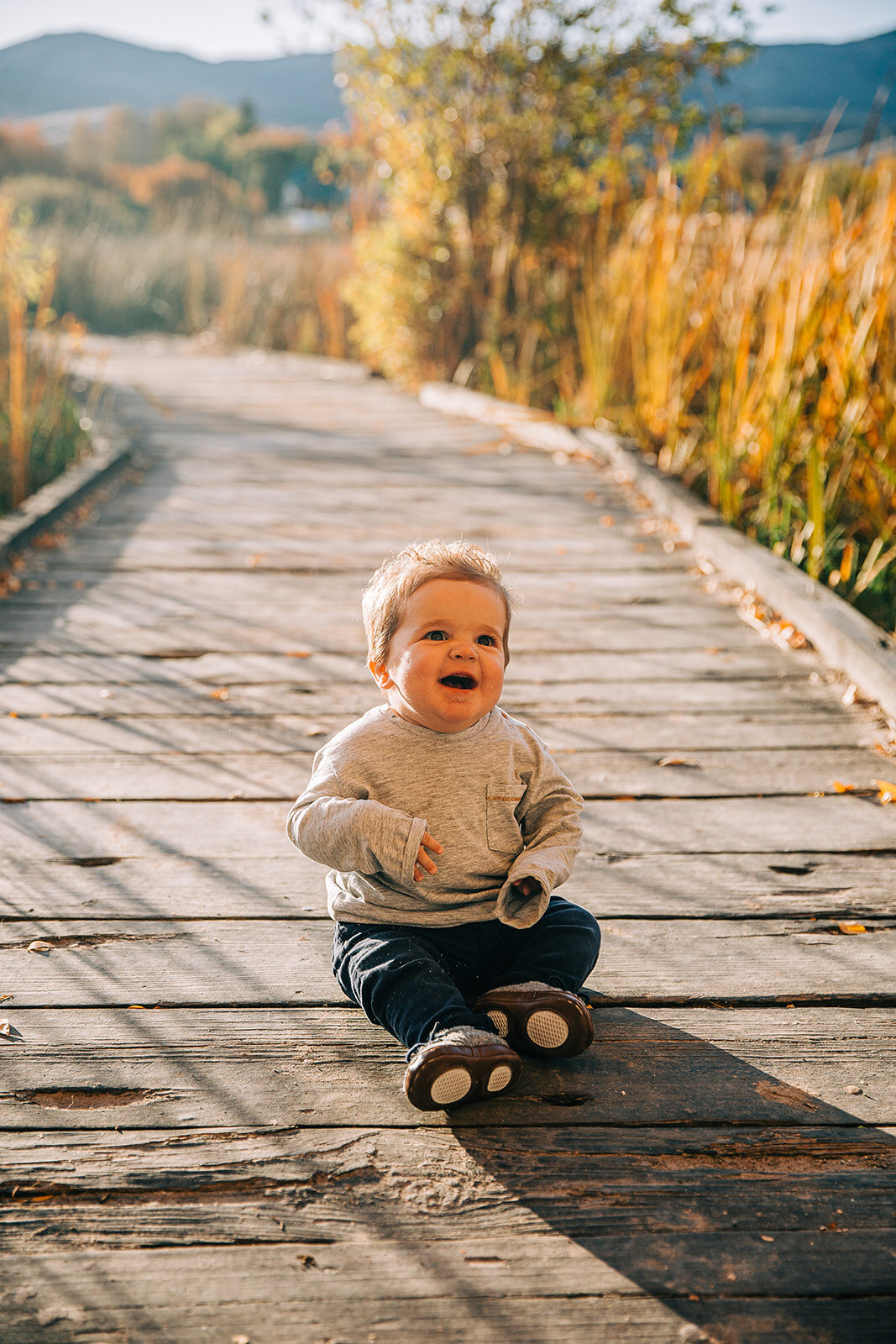  baby boy sitting on the boardwalk baby fashion boardwalk family pictures garden city park bear lake utah together again fields of gold mountains lakeside photos professional photographers in utah utah family photographers extended family siblings fa