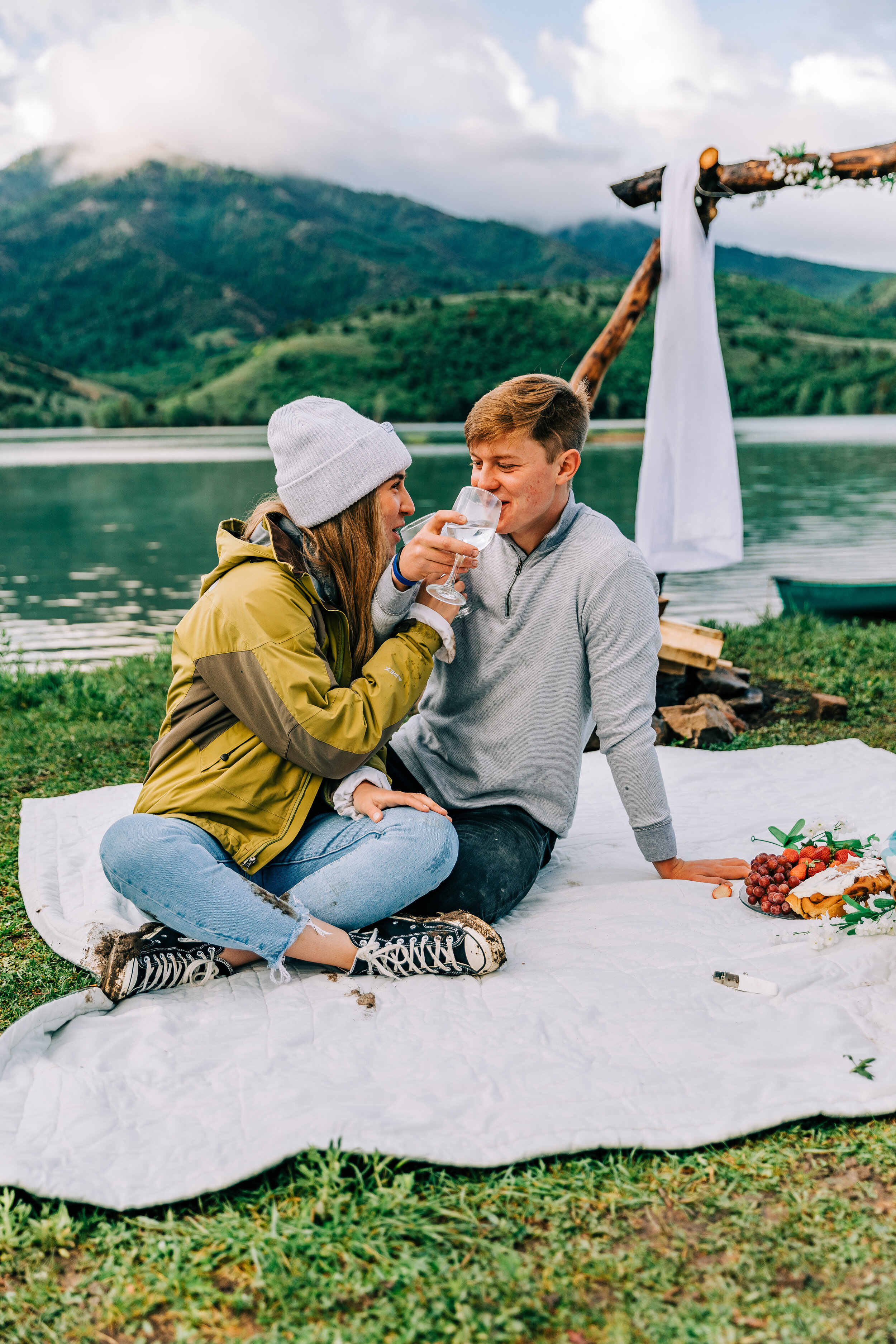  A newly engaged couple sharing their first drink together in an outdoor boho picnic in Paradise Utah. Porcupine Dam couple goals life goals surprise proposal photo shoot session professional Utah photographer Bella Alder Photography sitting couple p