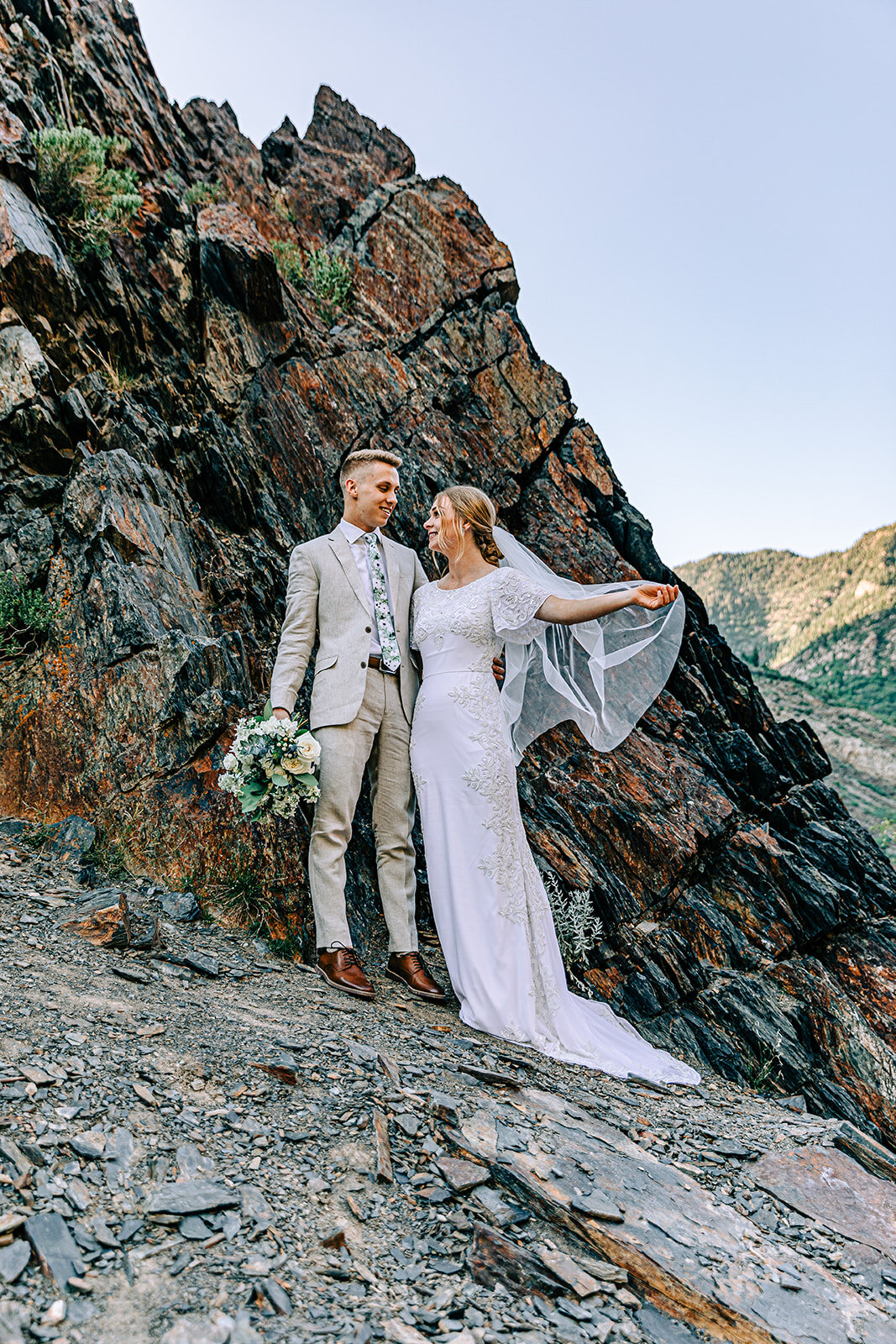  A beautiful bride holding her veil while looking at her groom in a boho chic style wedding photo shoot. Bridal pose inspiration ideas and goals couple pose inspiration professional Utah wedding photographer formal wedding photo shoot inspiration ide