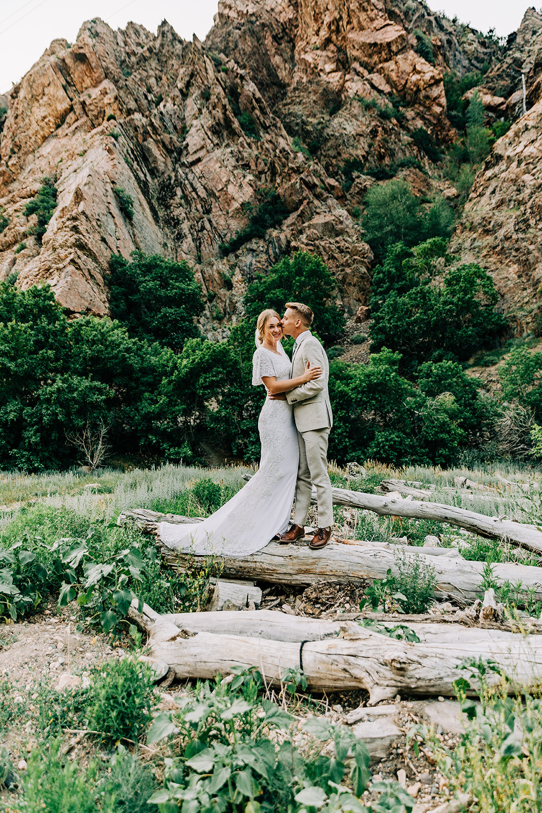  A handsome groom kissing his bride in a romantic outdoor formal wedding photo shoot by Bella Alder Photography. Cottonwood Canyon Salt Lake City, Utah formals professional Utah photographer wedding photography hugging couple pose inspiration ideas a
