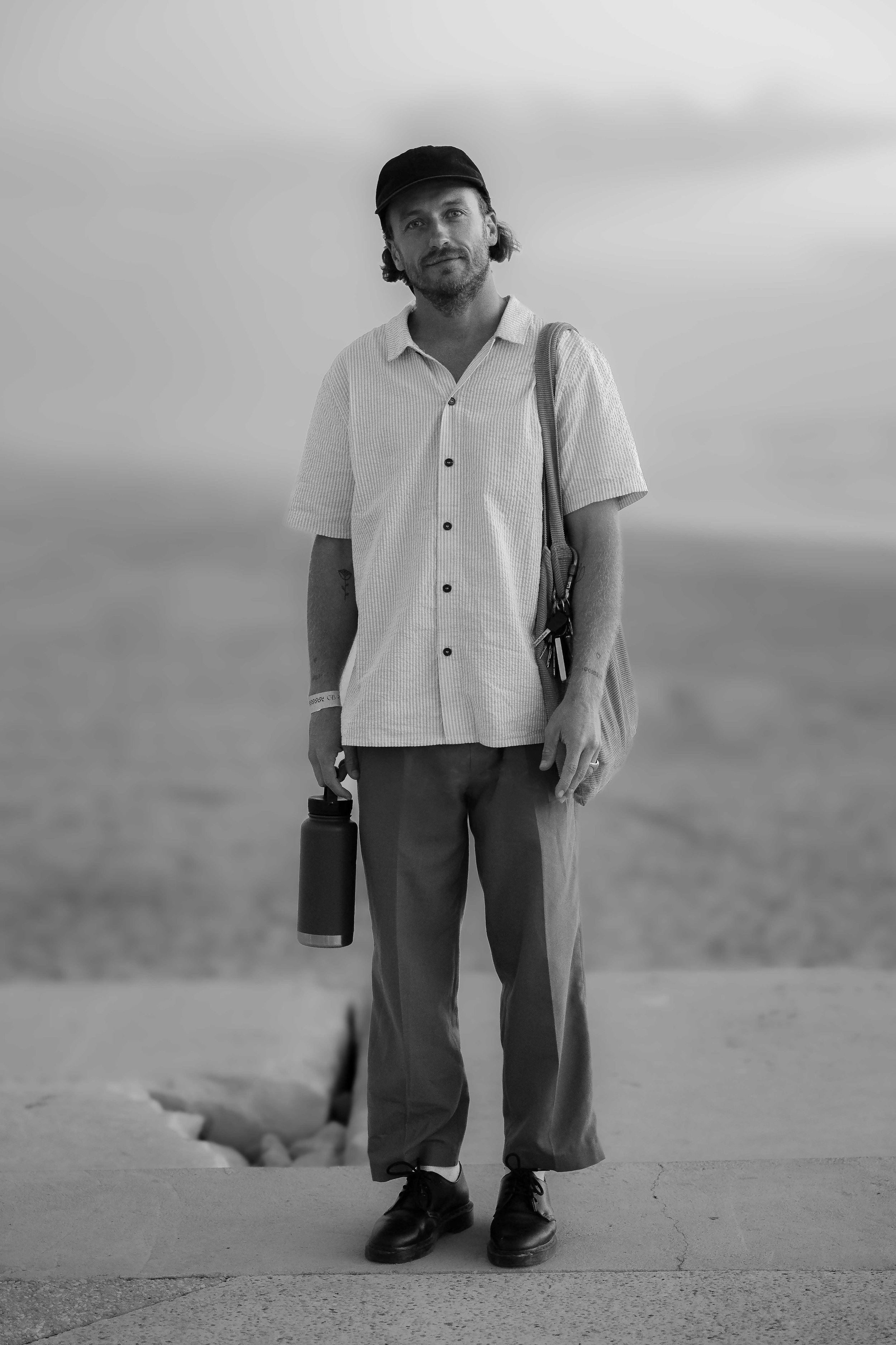 Black and white photo of Simon Fitz, standing in Figueria da Foz, Portugal during the Gliding Barnacles Festival..doing his favorite thing "Surf Photography"