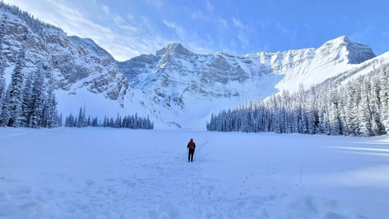 Snow-covered Rawson Lake surrounded by towering mountains during a winter hike in Kananaskis Country.