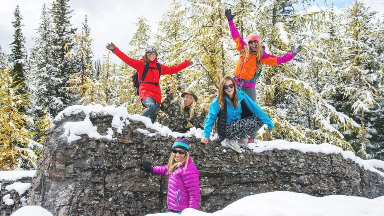 Group of friends hiking in snowy Banff forest, showing the best time to visit Banff for winter scenery. 