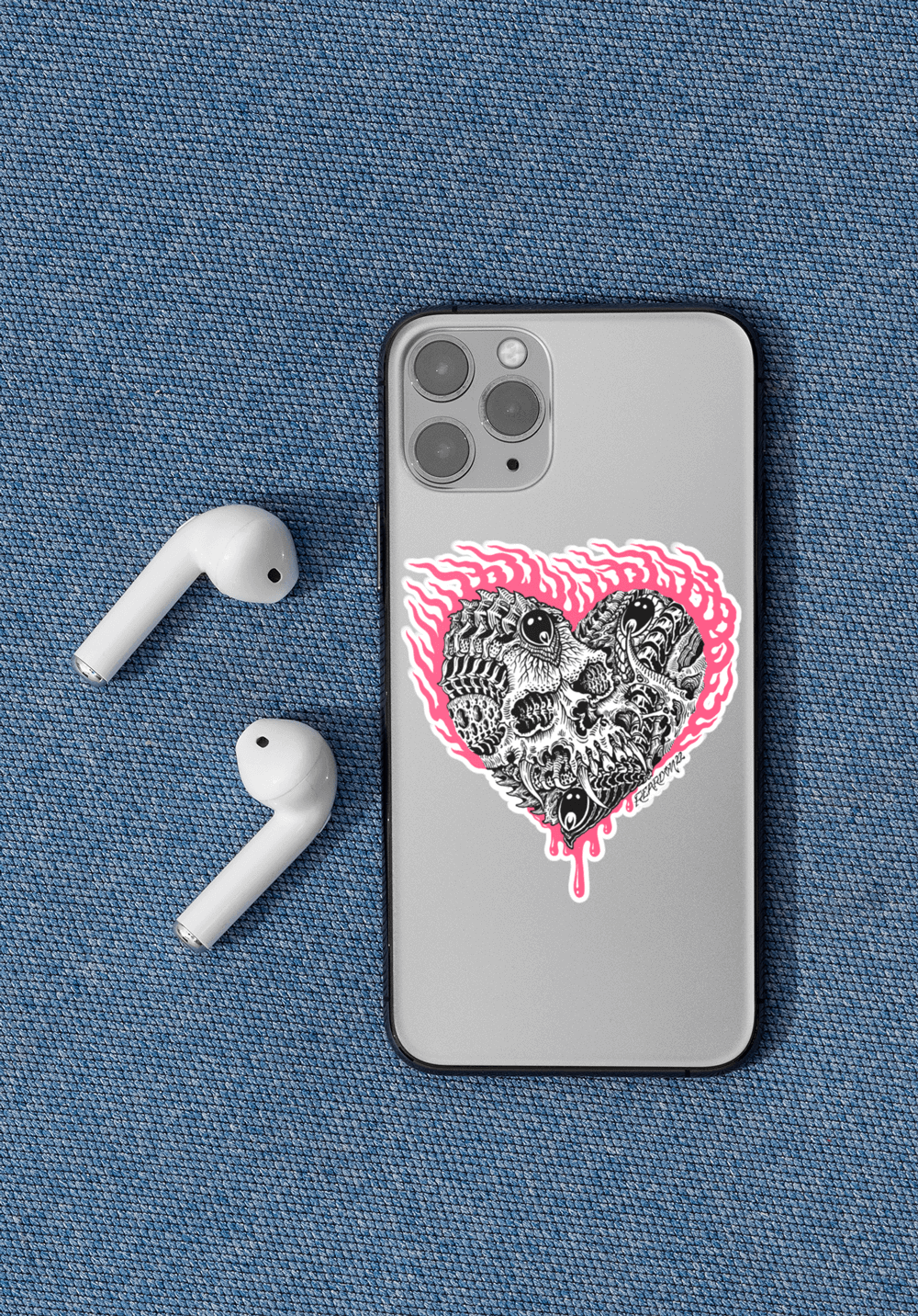 Small biomech heart sticker in black white and pink on a grey phone, laying next to earphones on a textured blue background