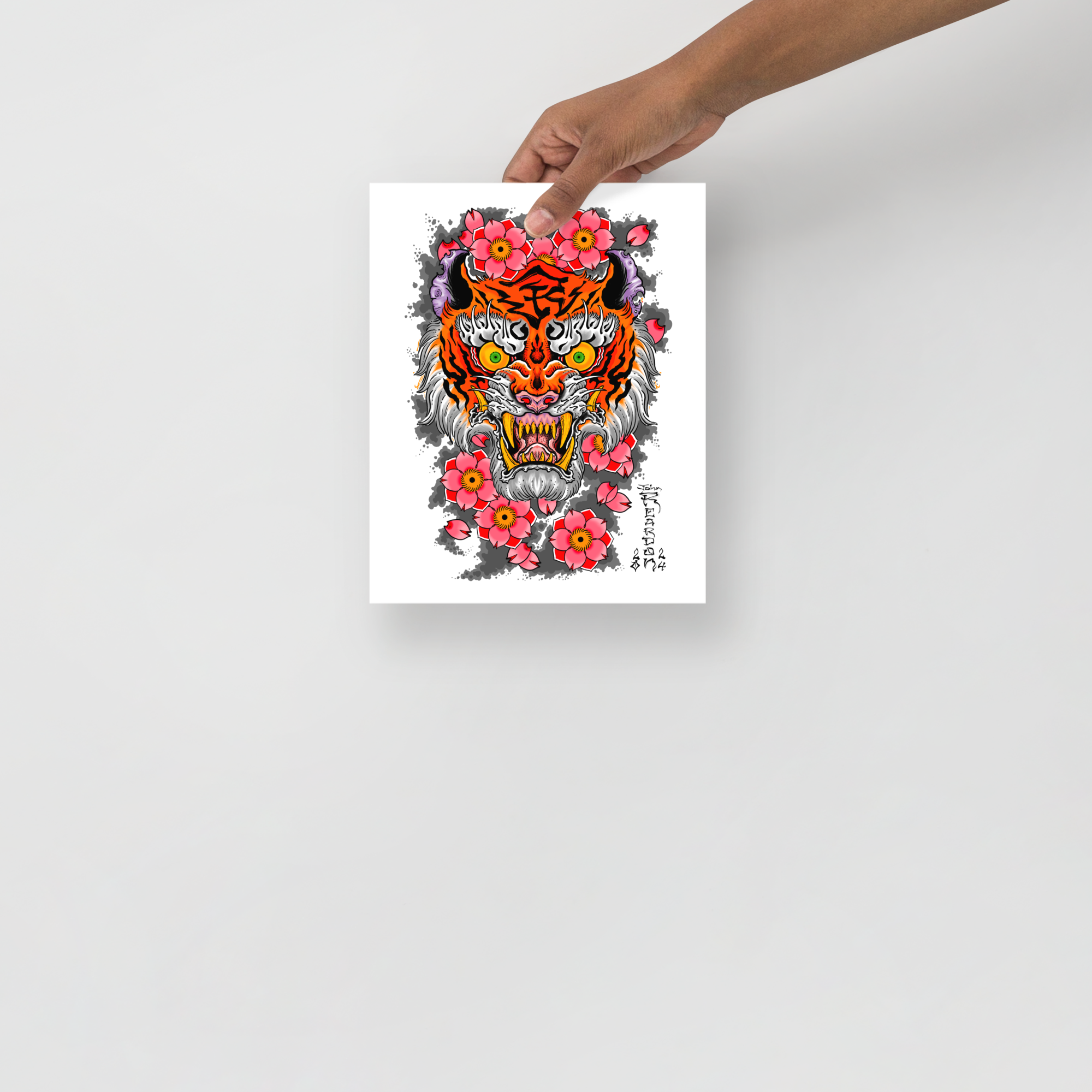 Small merch print of tiger and flowers on white background being held in front of grey tattoo shop wall