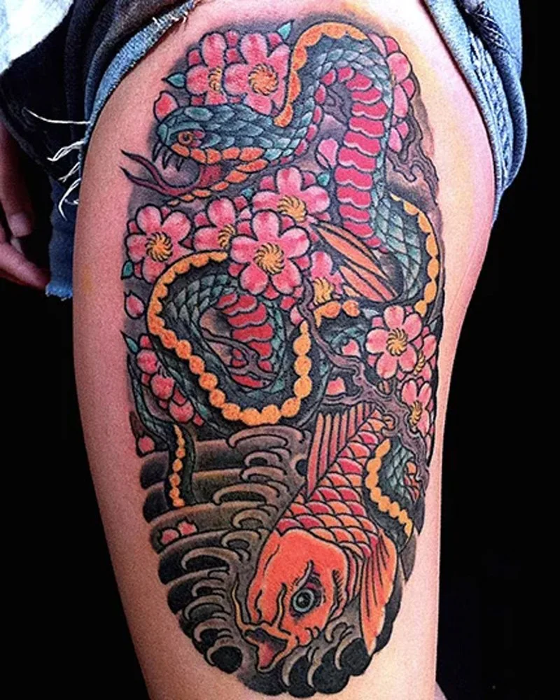 Snake and koi fish with cherry blossoms tattoo on a thigh.