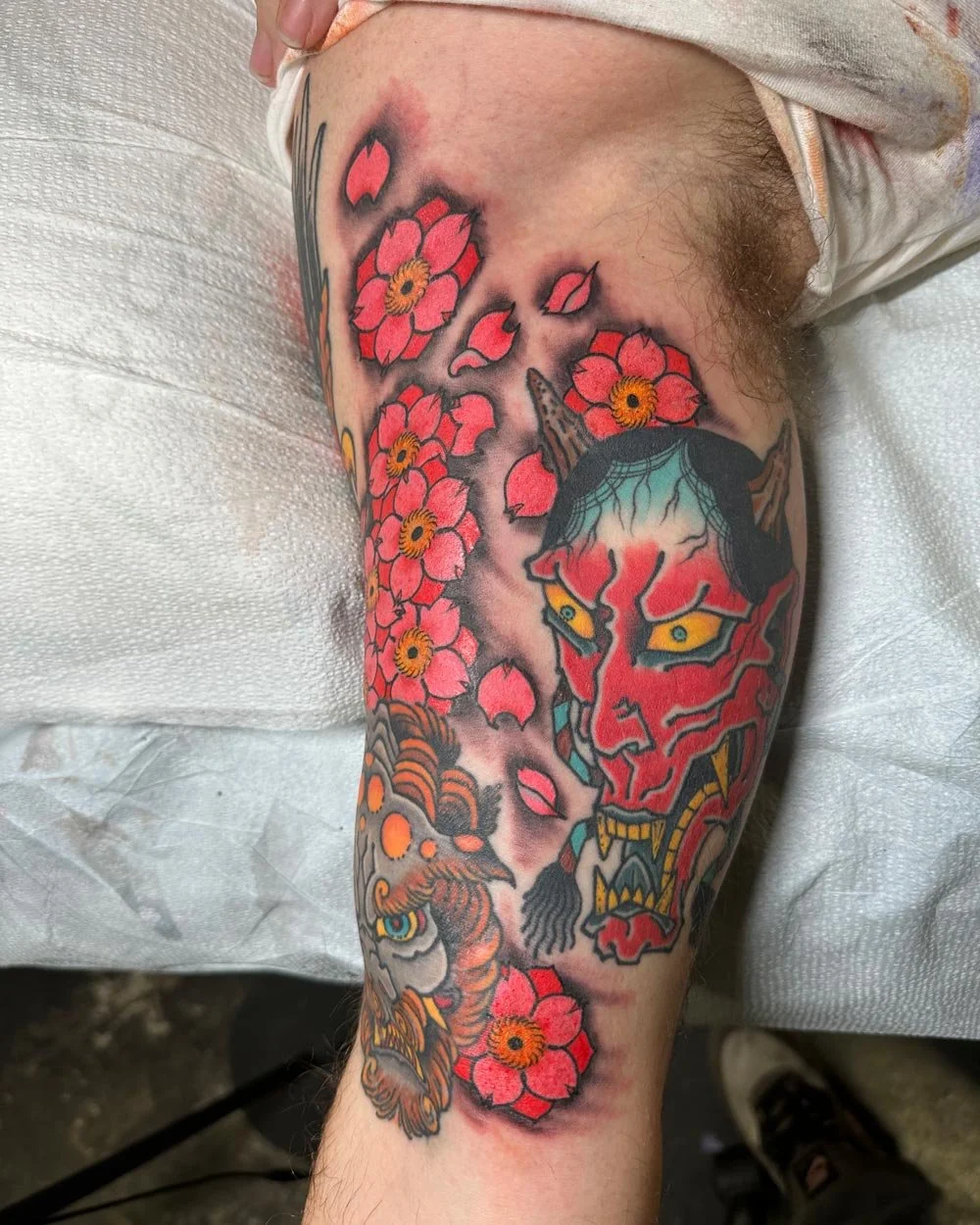 Japanese color tattoo with cherry blossoms, a Hanya mask, and a Foo dog.