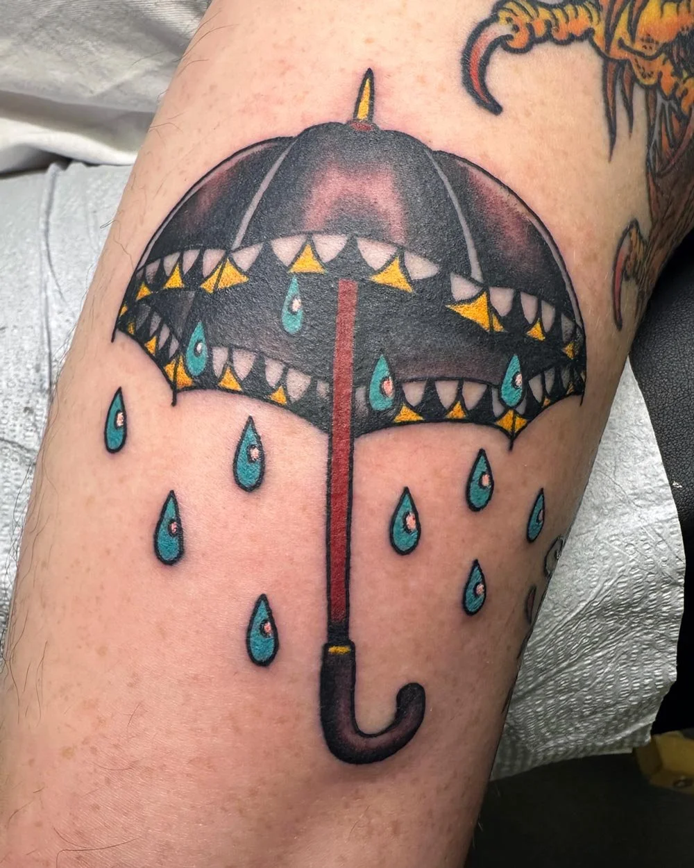 Traditional color tattoo of an umbrella with rain tattooed in Brooklyn NY.