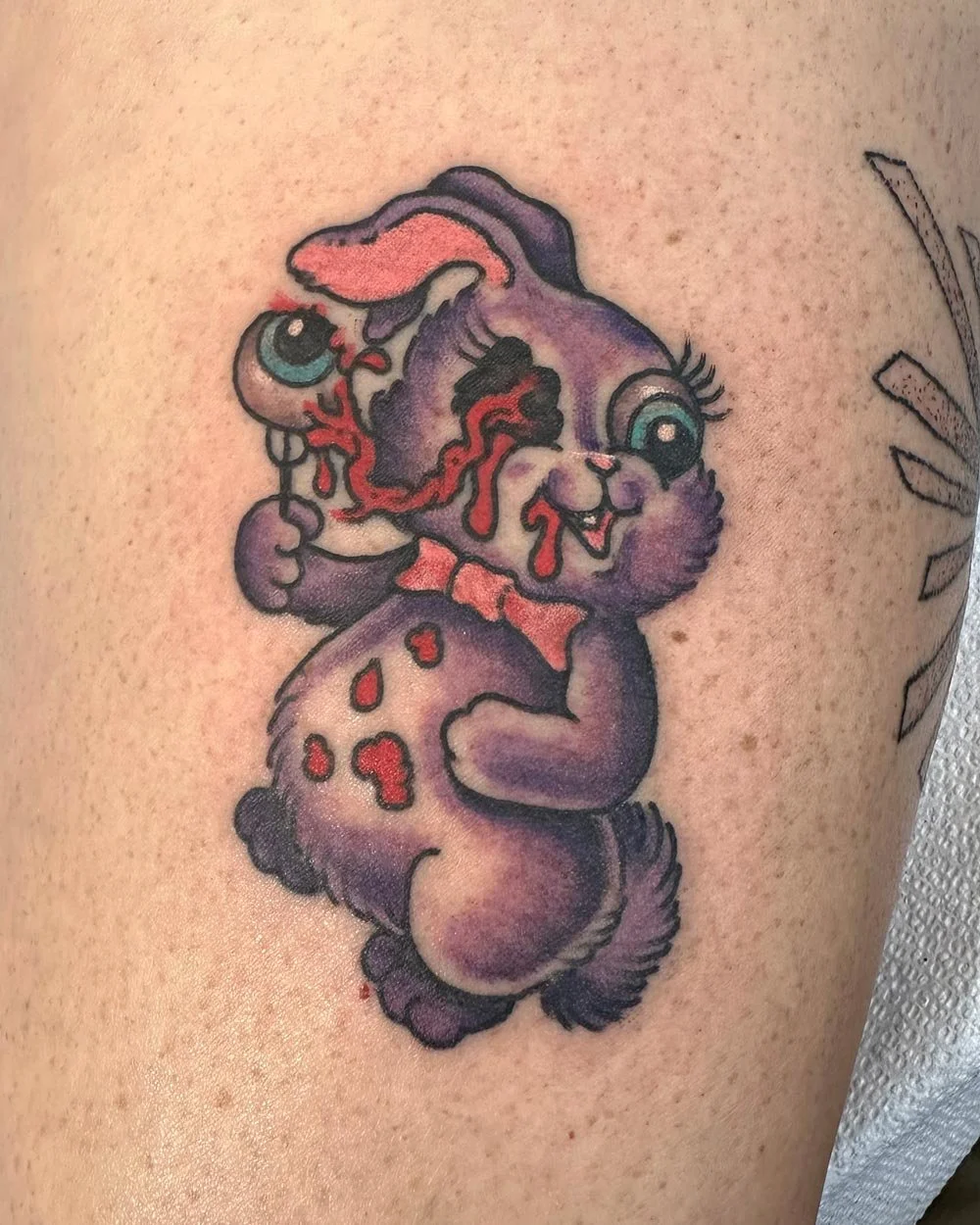Purple zombie bunny tattoo in color on a leg.